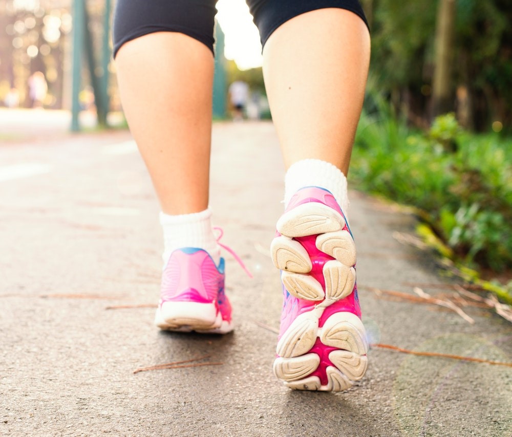 A close-up of pink sneakers worn by someone walking in town