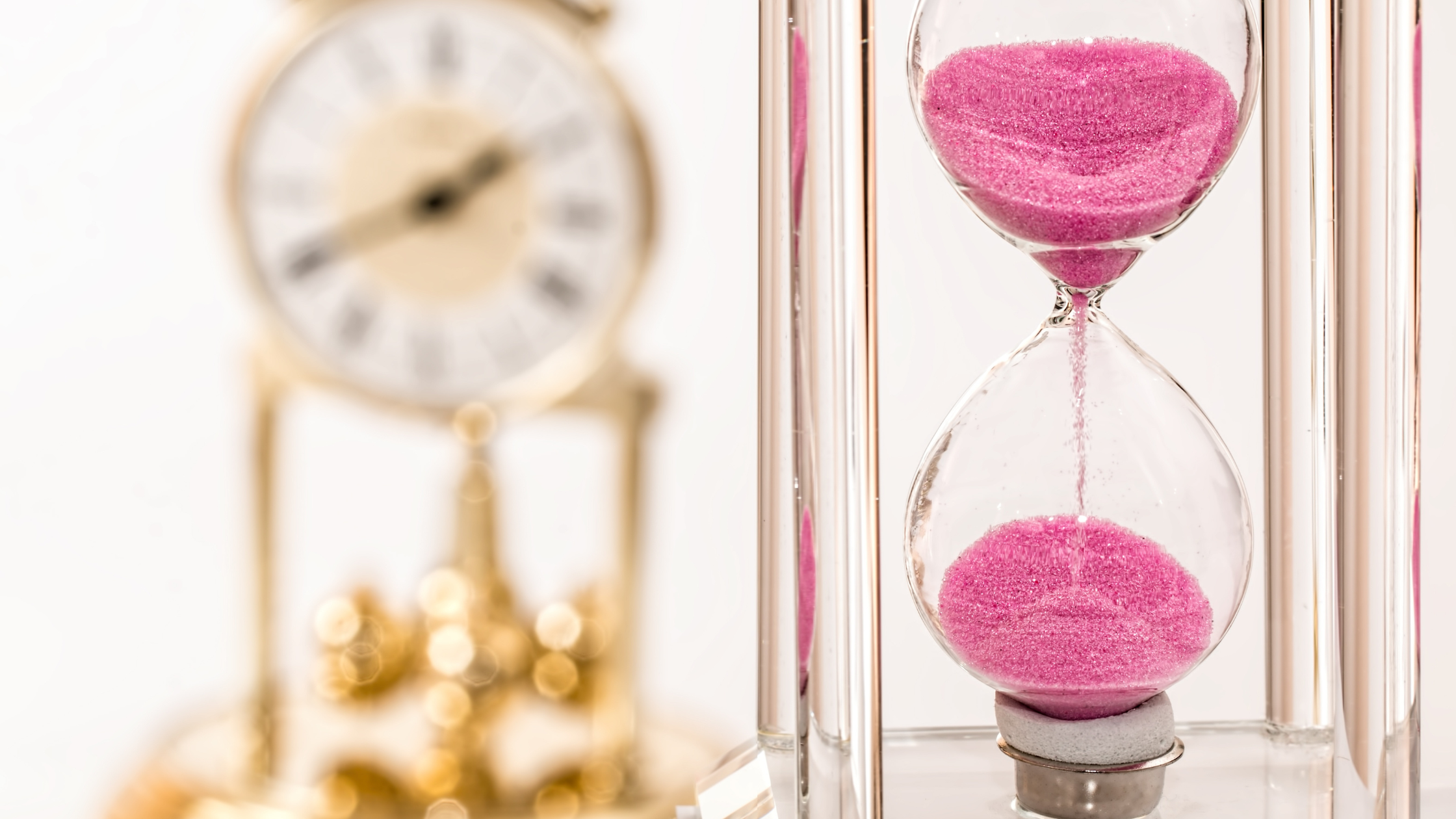 hourglass full of pink sand drains into the lower half