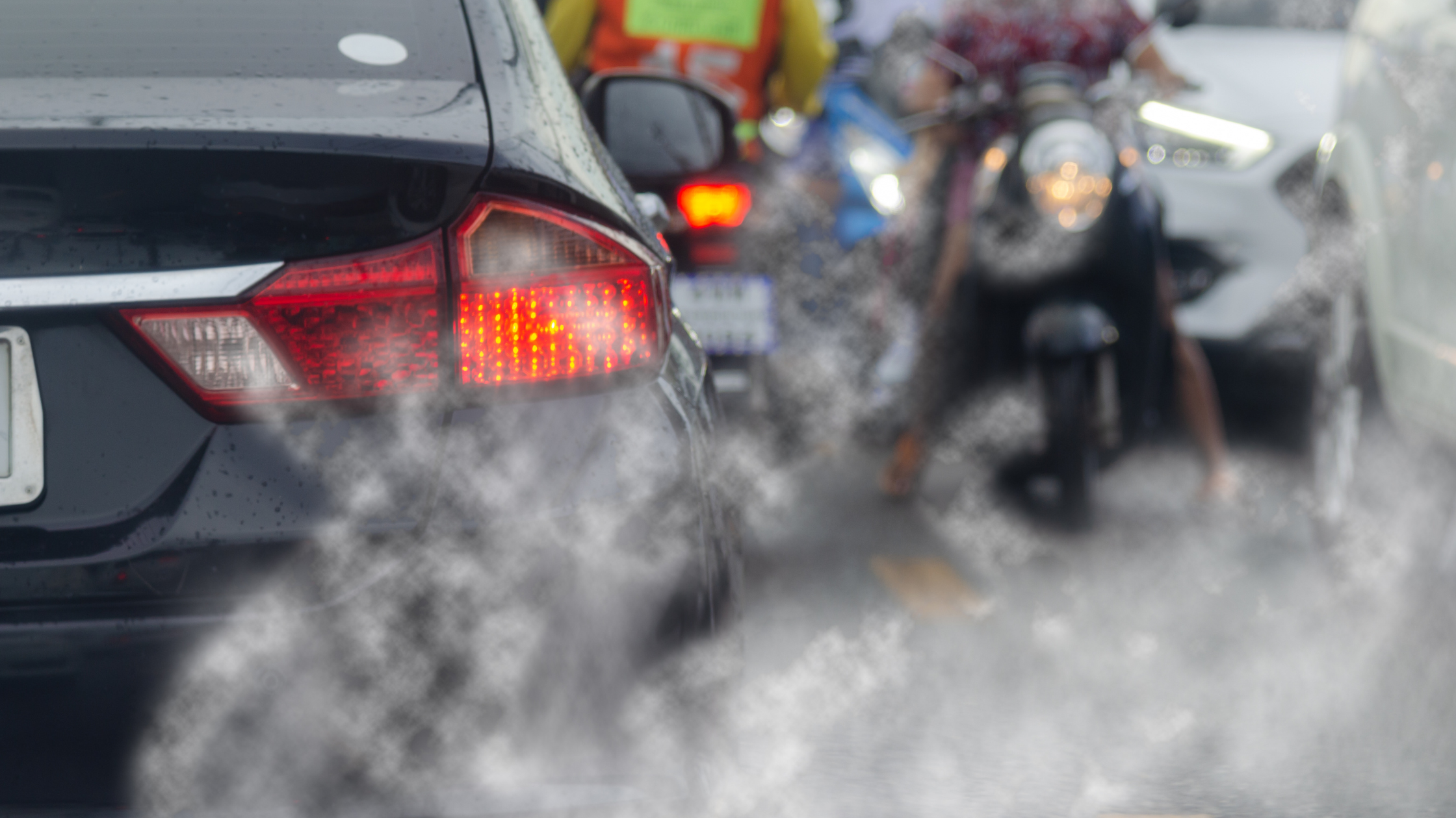 exhaust billows from cars stuck in a traffic jam