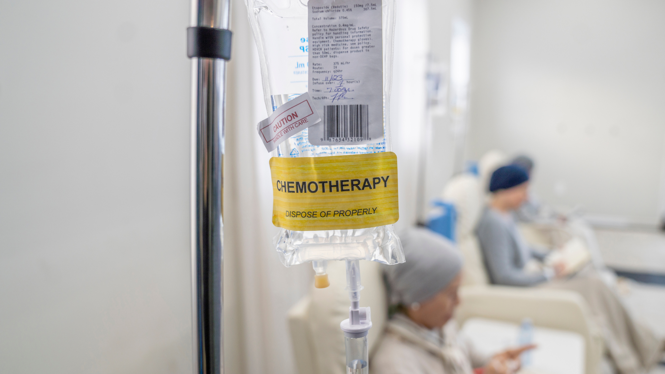 closeup of a chemotherapy bag, patients in the background