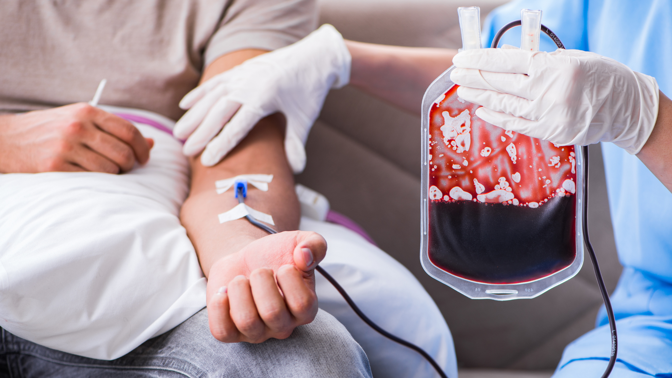 nurse runs an IV of blood to the arm of a seated patient