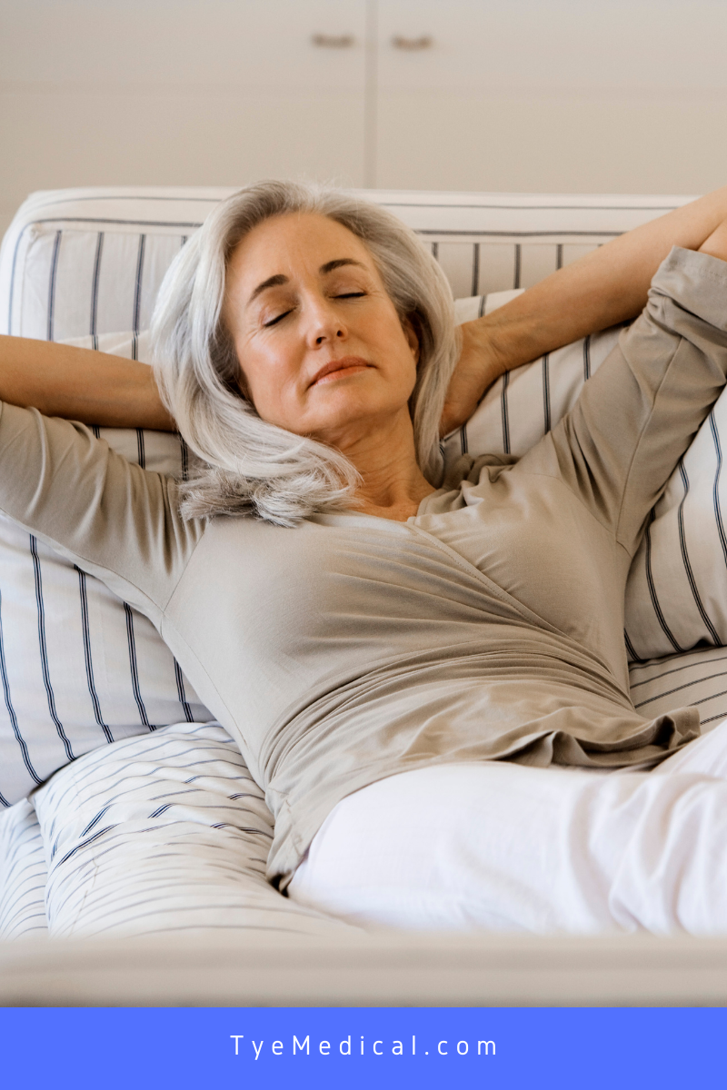 Older woman relaxing on the bed with hands behind her head