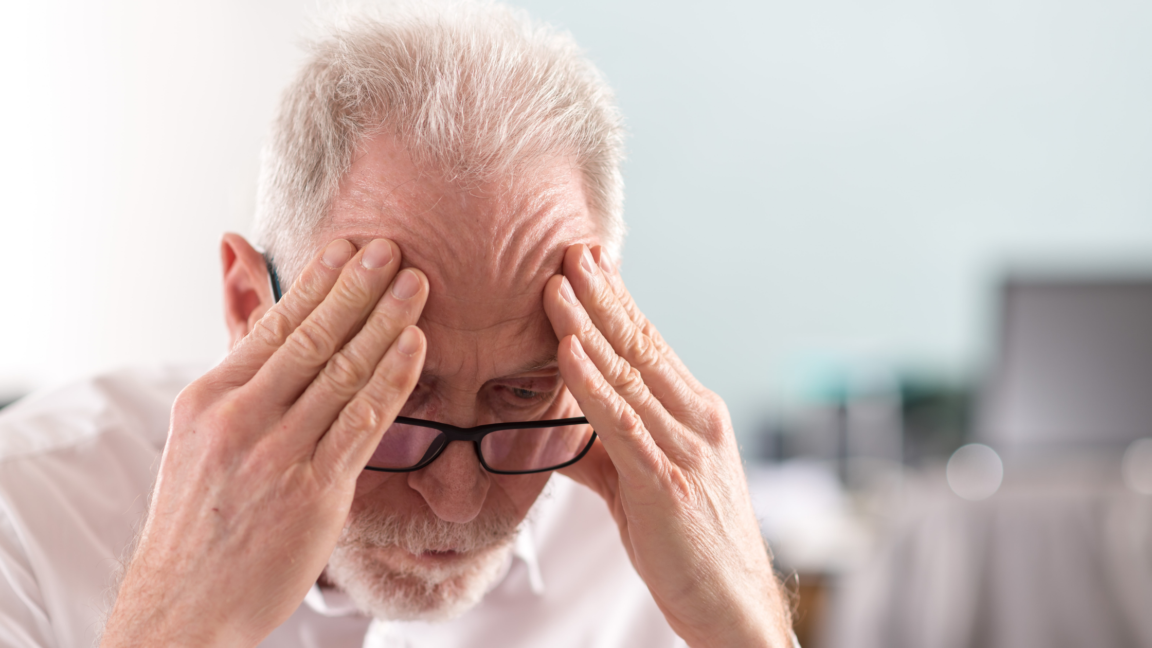 Stressed man massages his forehead with both hands