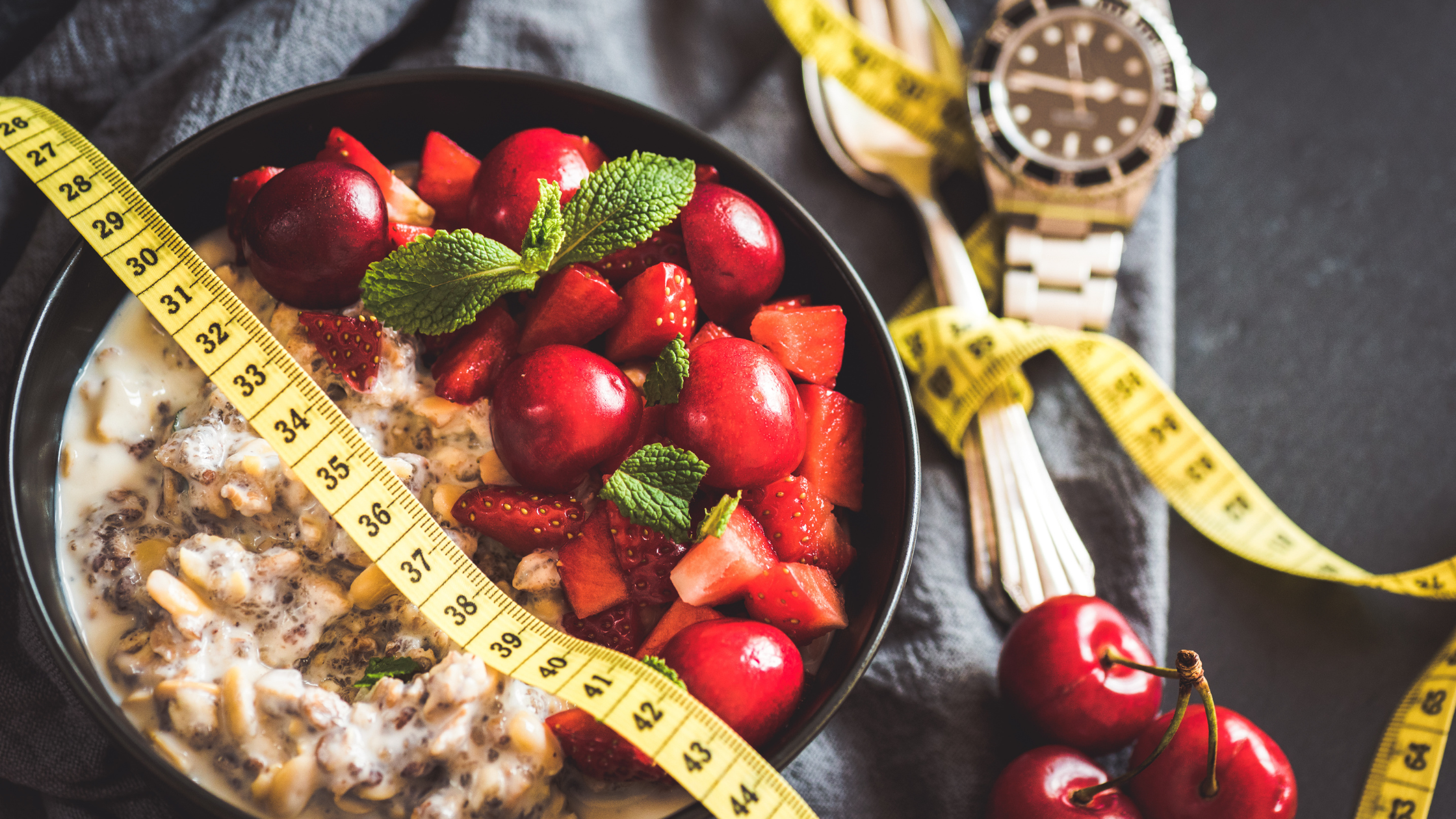 a measuring tape curls around utensils and runs over a bowl of grains and veggies