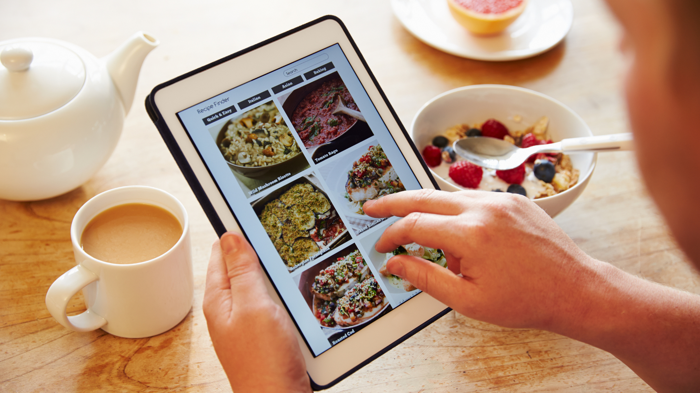 hands scroll through an ipad with recipes onscreen