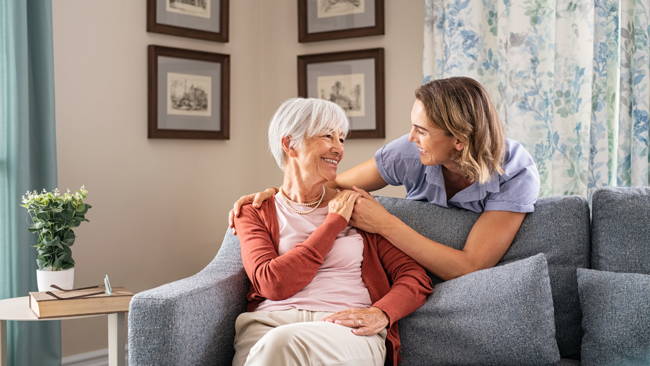 younger woman and senior woman talk happily in a living room