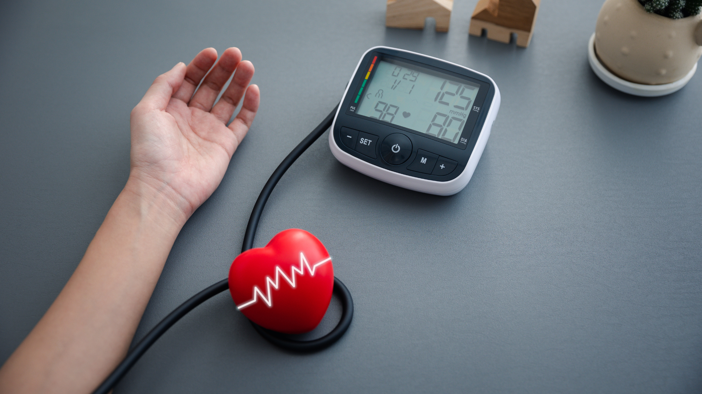 adult arm laying on a tabletop with a blood pressure monitor taking measurements