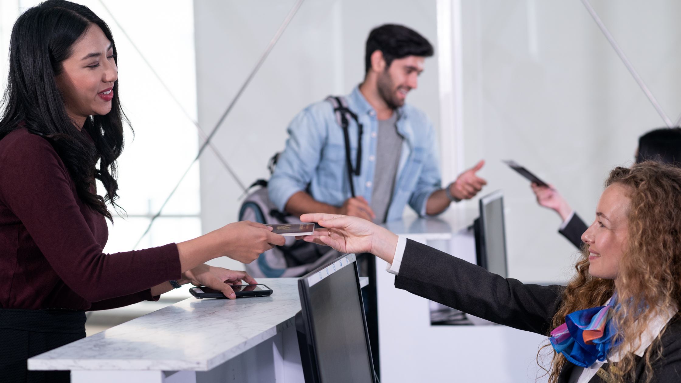 two people interacting with airline agents at the counter