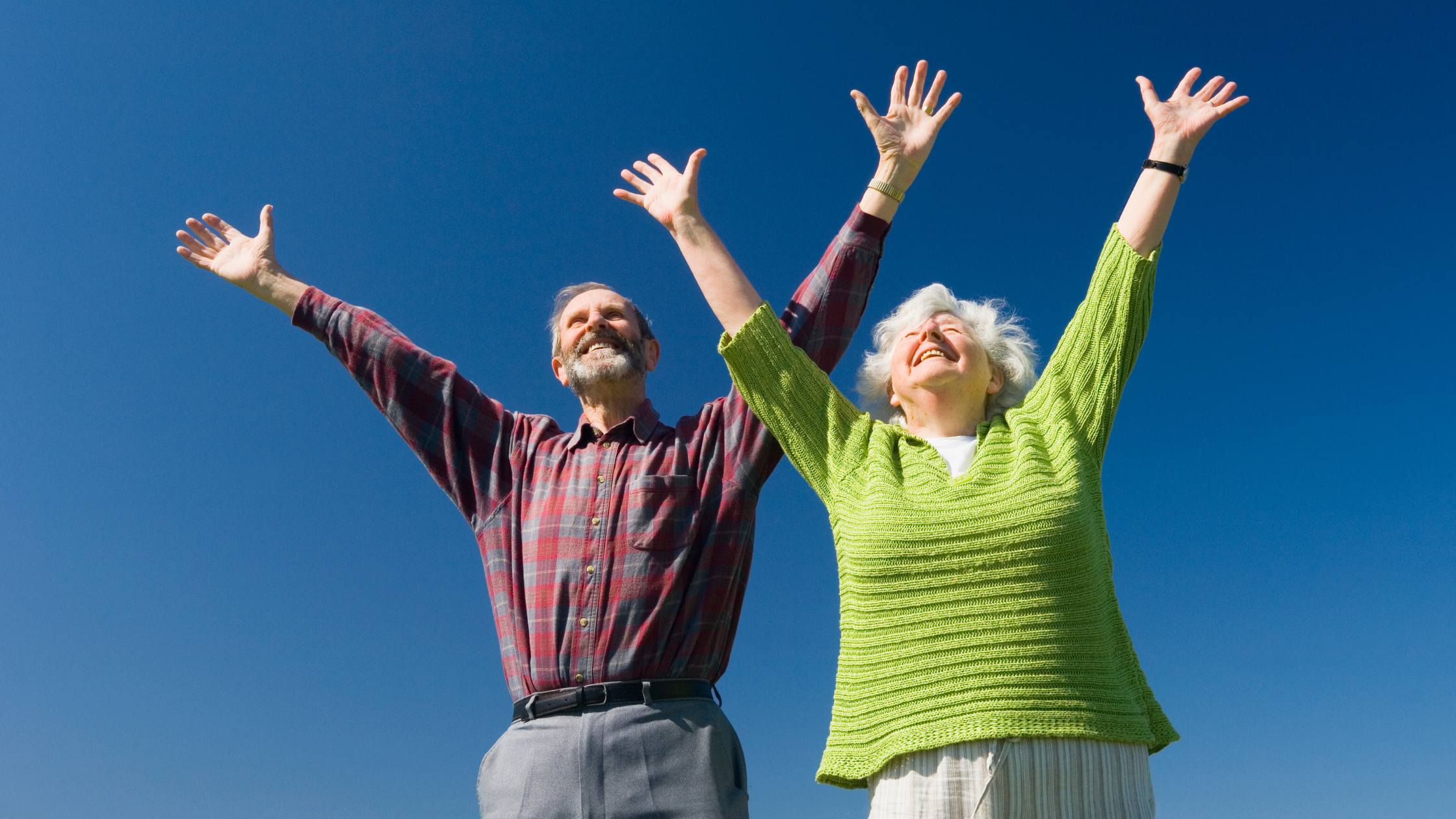 smiling seniors pose with both hands in the air