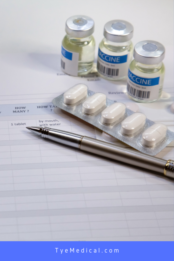 A steel pen next to pill tablets, and small bottles of vaccine