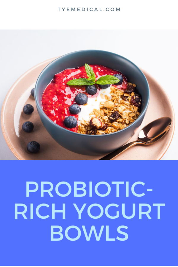A bowl of yogurt topped with nuts, blueberries, and raspberry