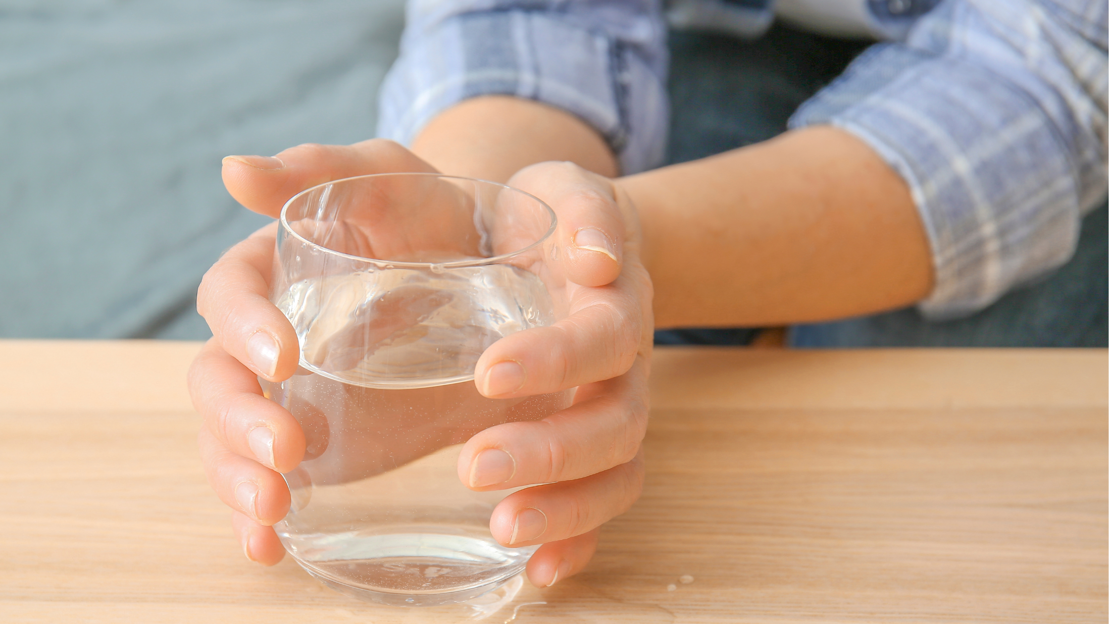 hands grip a full glass of water