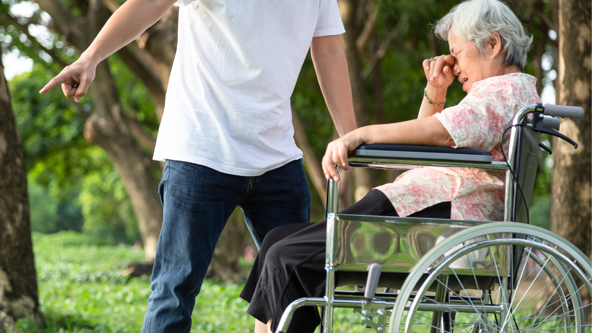 man pointing away from an upset senior woman in a wheelchair