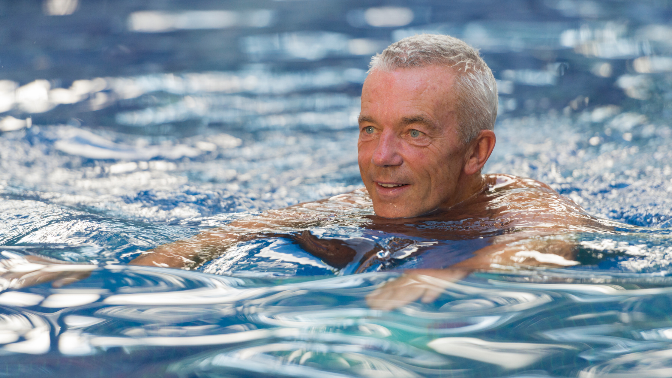 senior man swims in a pool