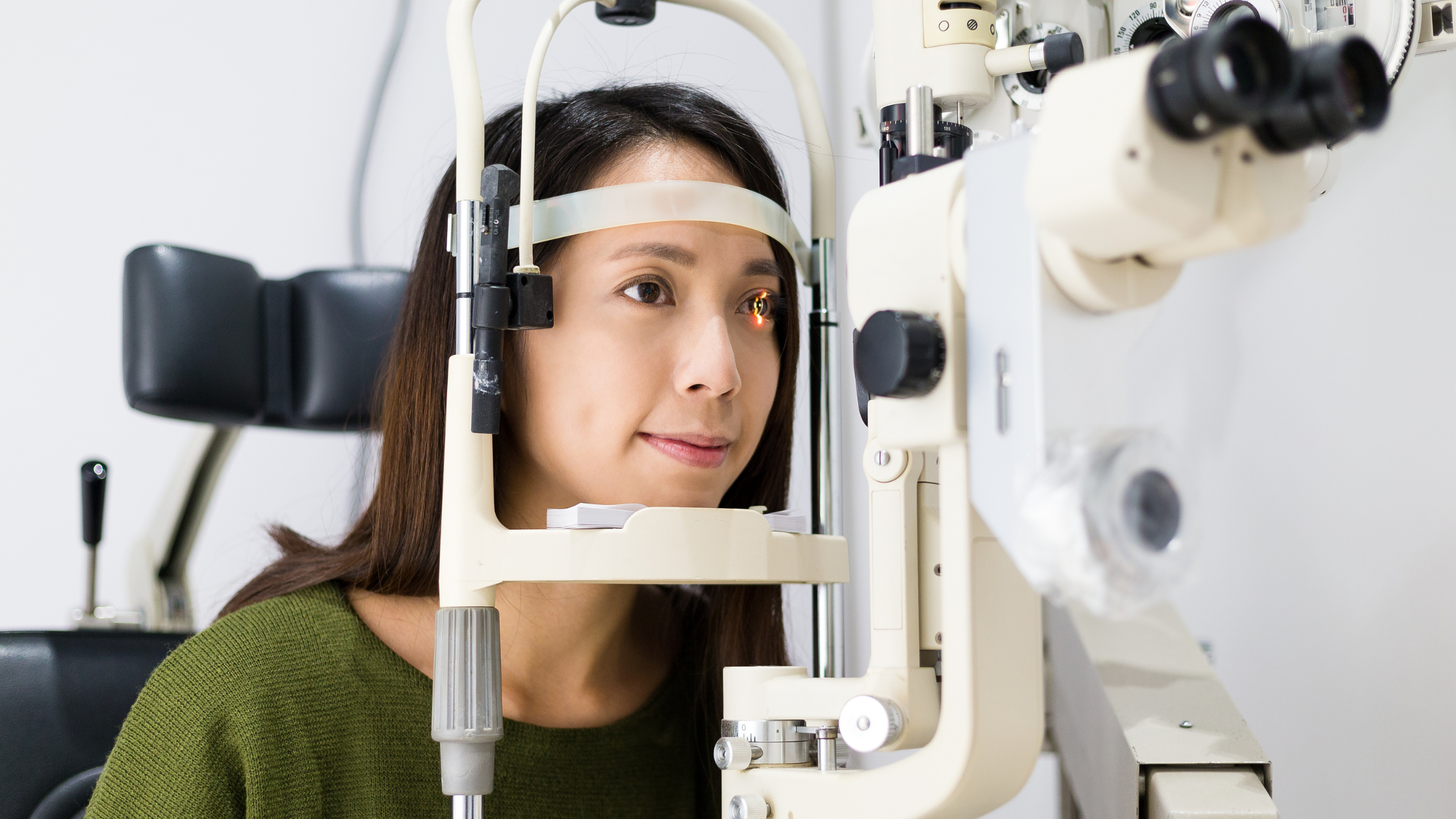 woman getting an eye exam from the machine that shines a light to look at the back of your eyeball puffs 