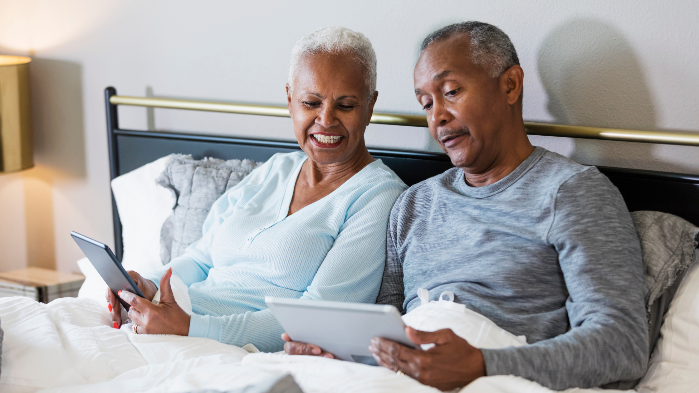 Older couple in bed looking at their tablets