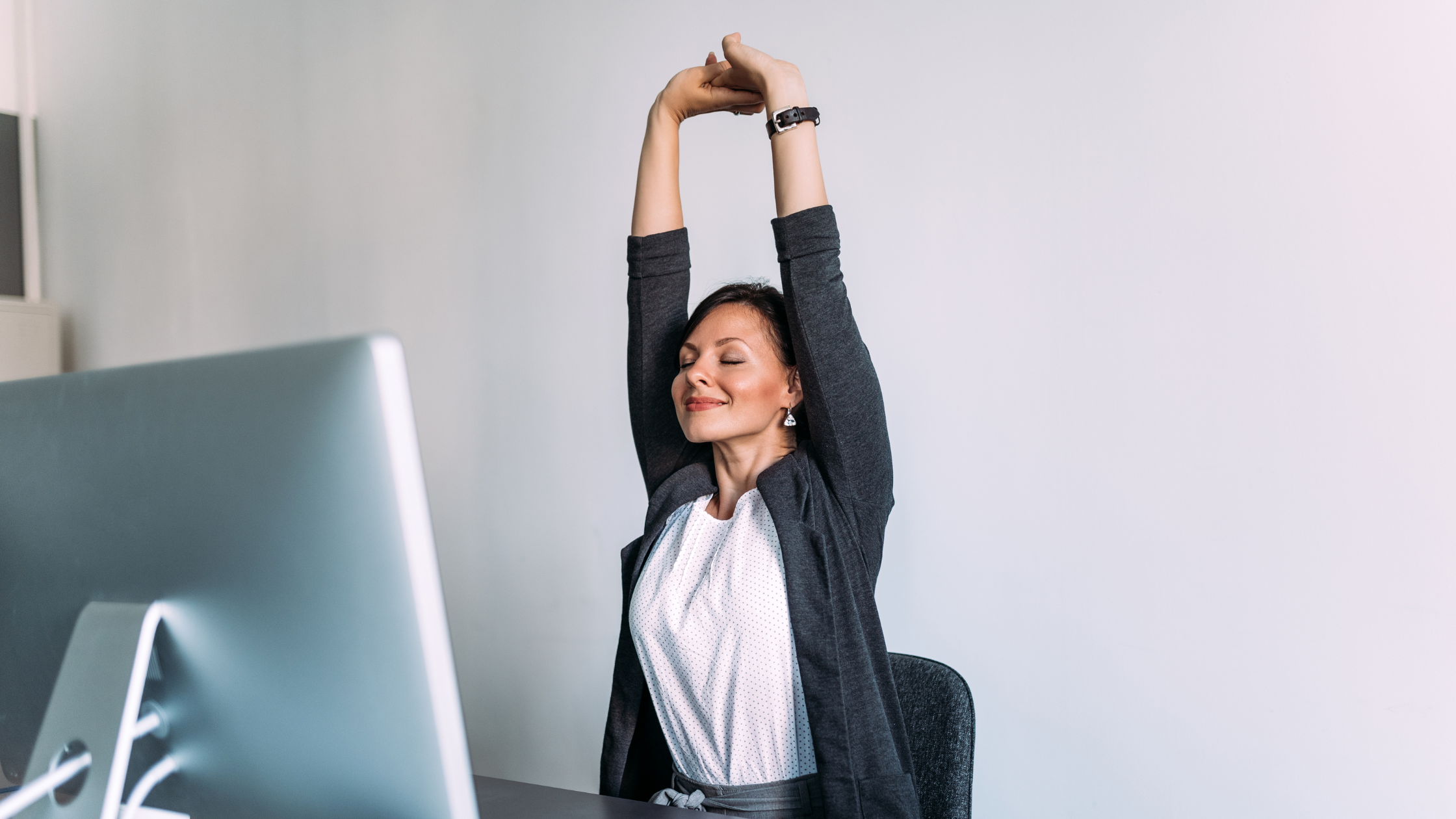 smiling woman stretches at her desk