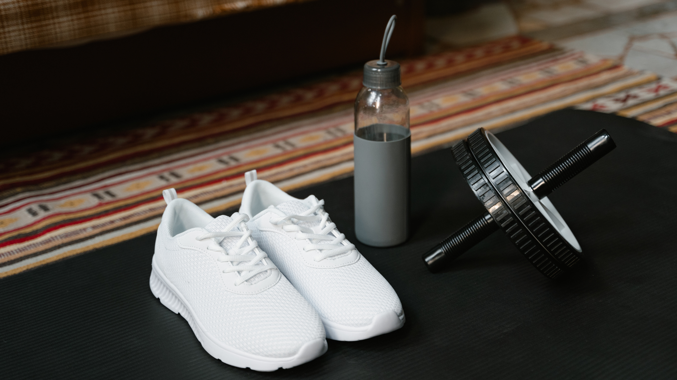 sneakers, a weight and a water bottle sit on a yoga mat