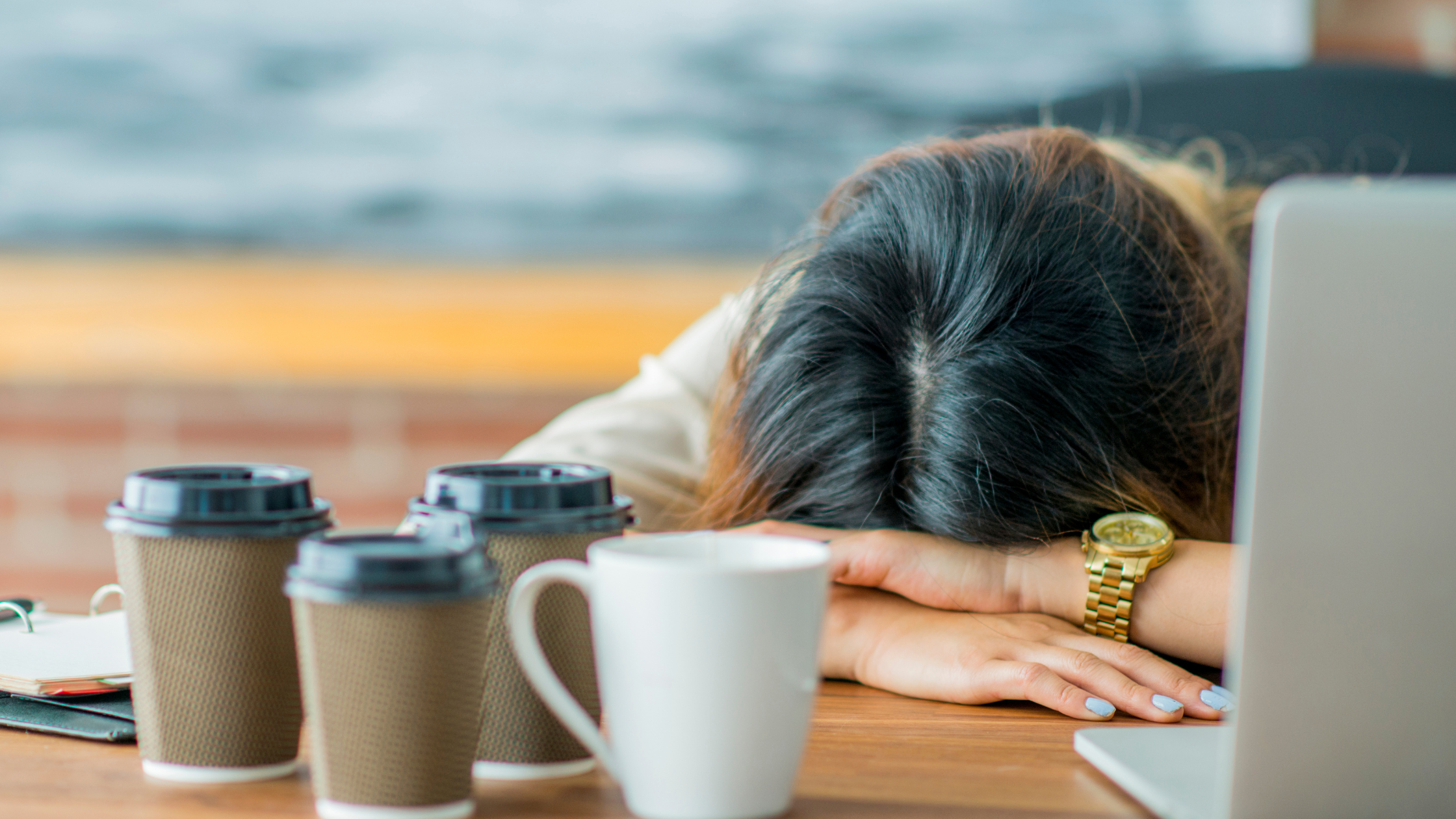 head down sleeping on a table surrounded by empty coffee cups