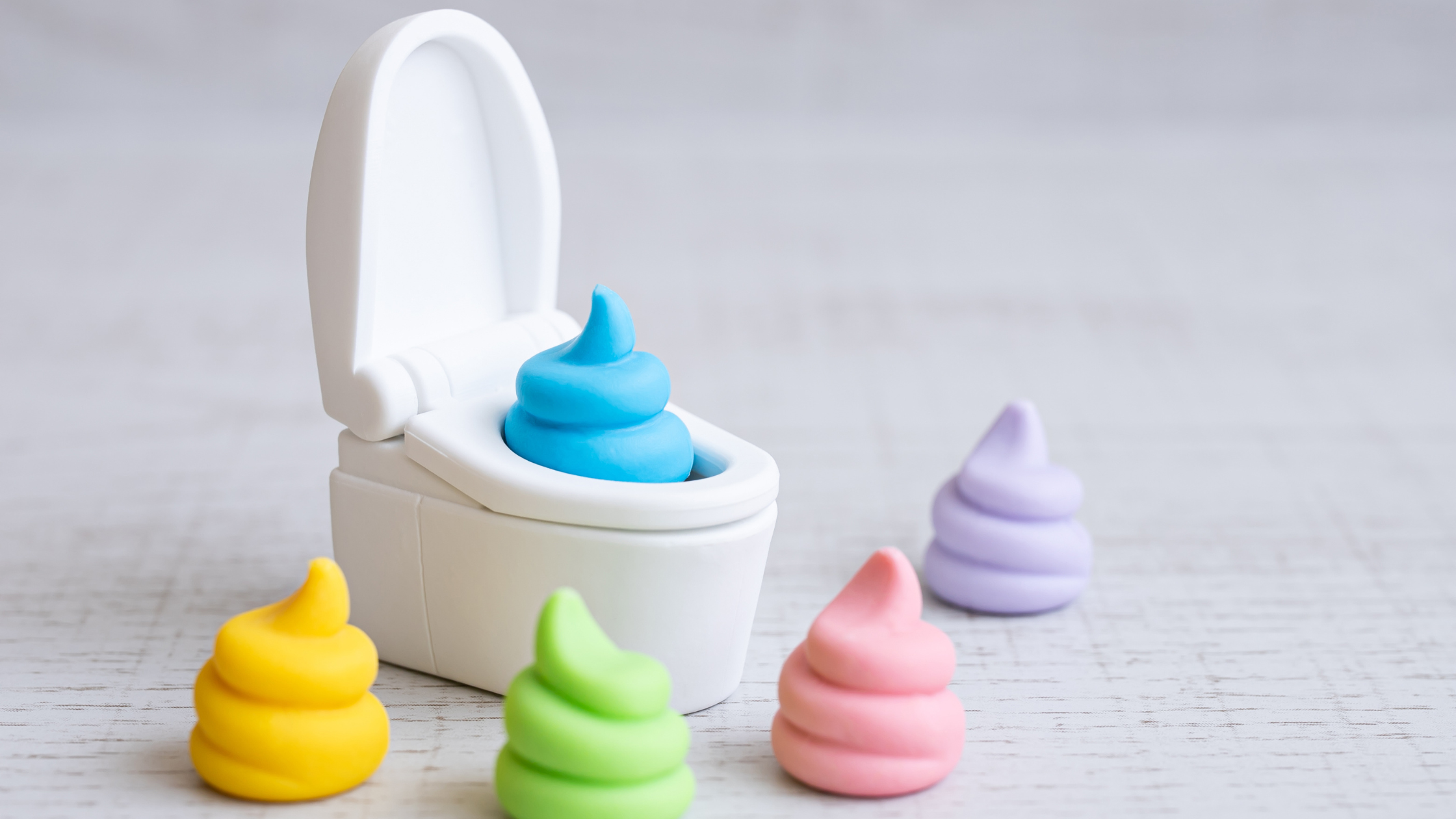 tiny plastic toilet surrounded by pastel piles of poop