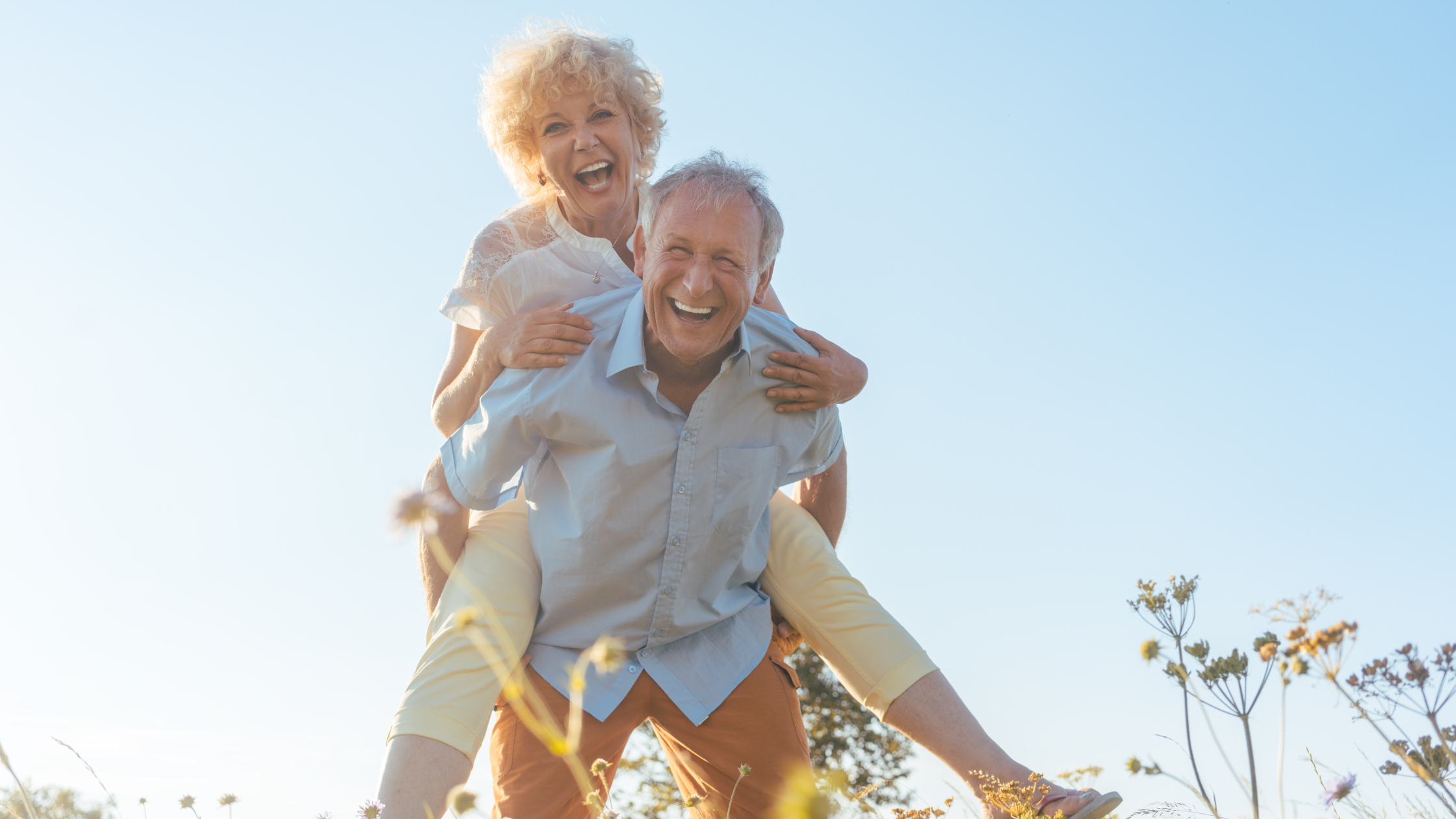 senior man with a senior woman on his back, both smile senior man with a senior woman on his back, both smile