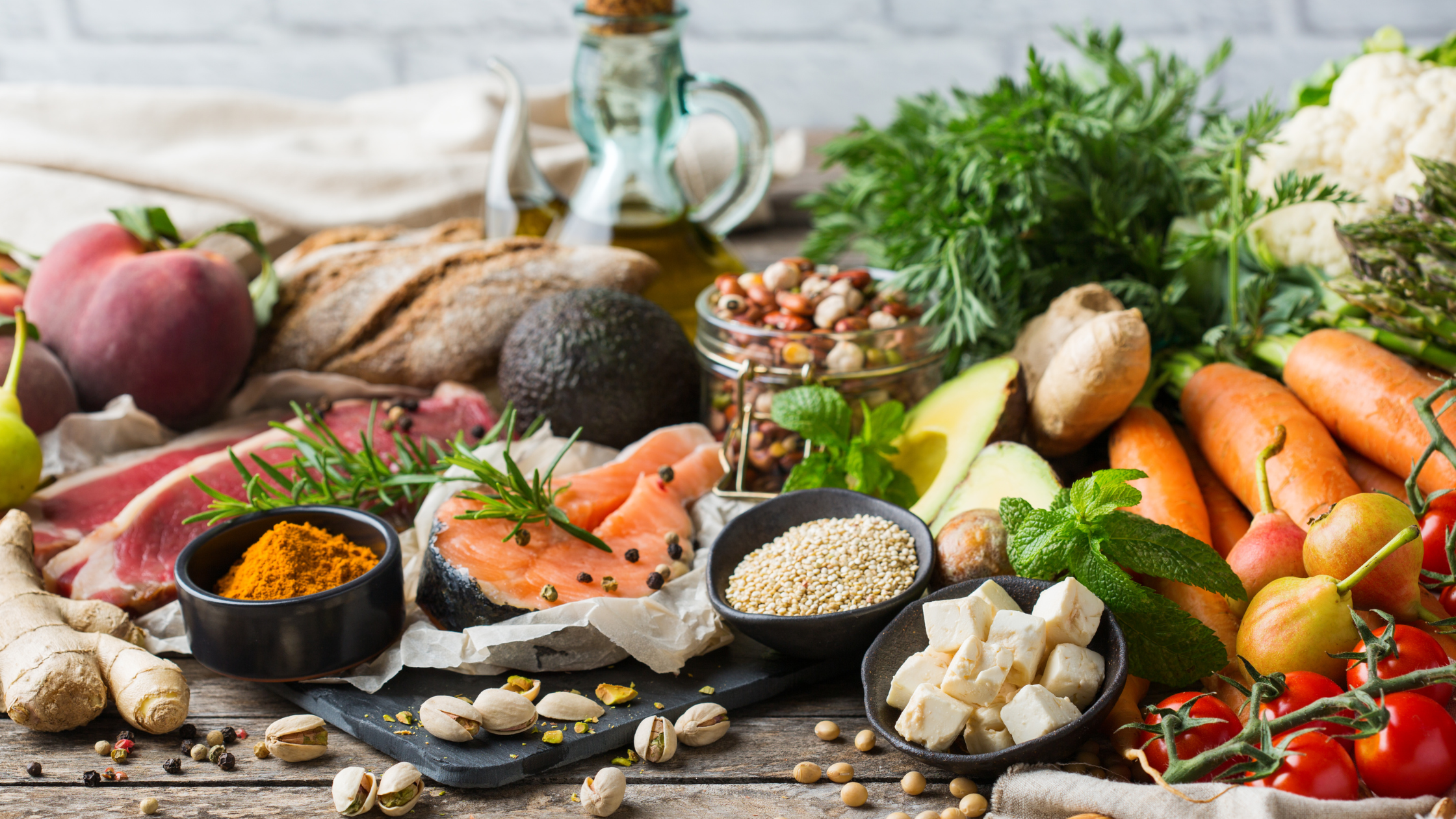 rustic tabletop covered in raw vegetables, nuts, and grains