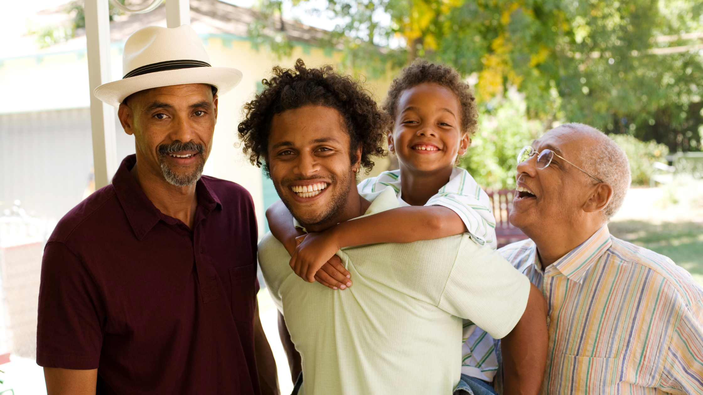 Generational family photo of a senior, a middle-aged man, a younger man, and a child on that man's shoulders