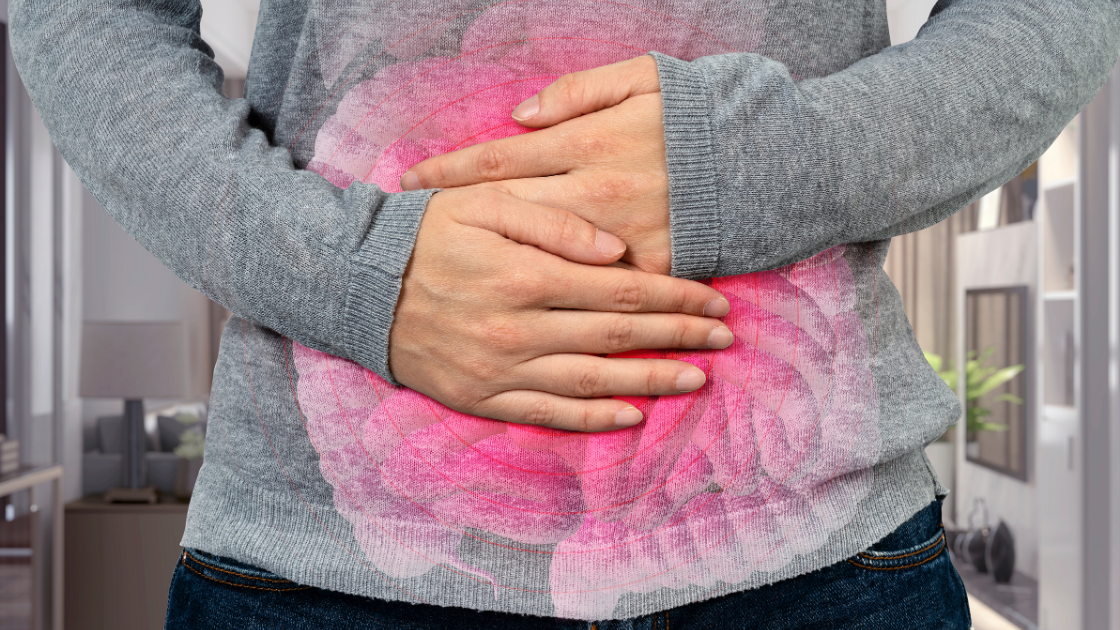 Woman holding stomach in discomfort, transparent digestive tract illustrated over her stomach