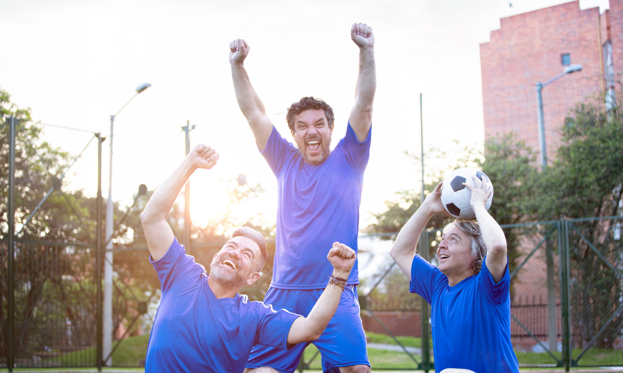 Three happy men playing soccer stopping to pose for photo