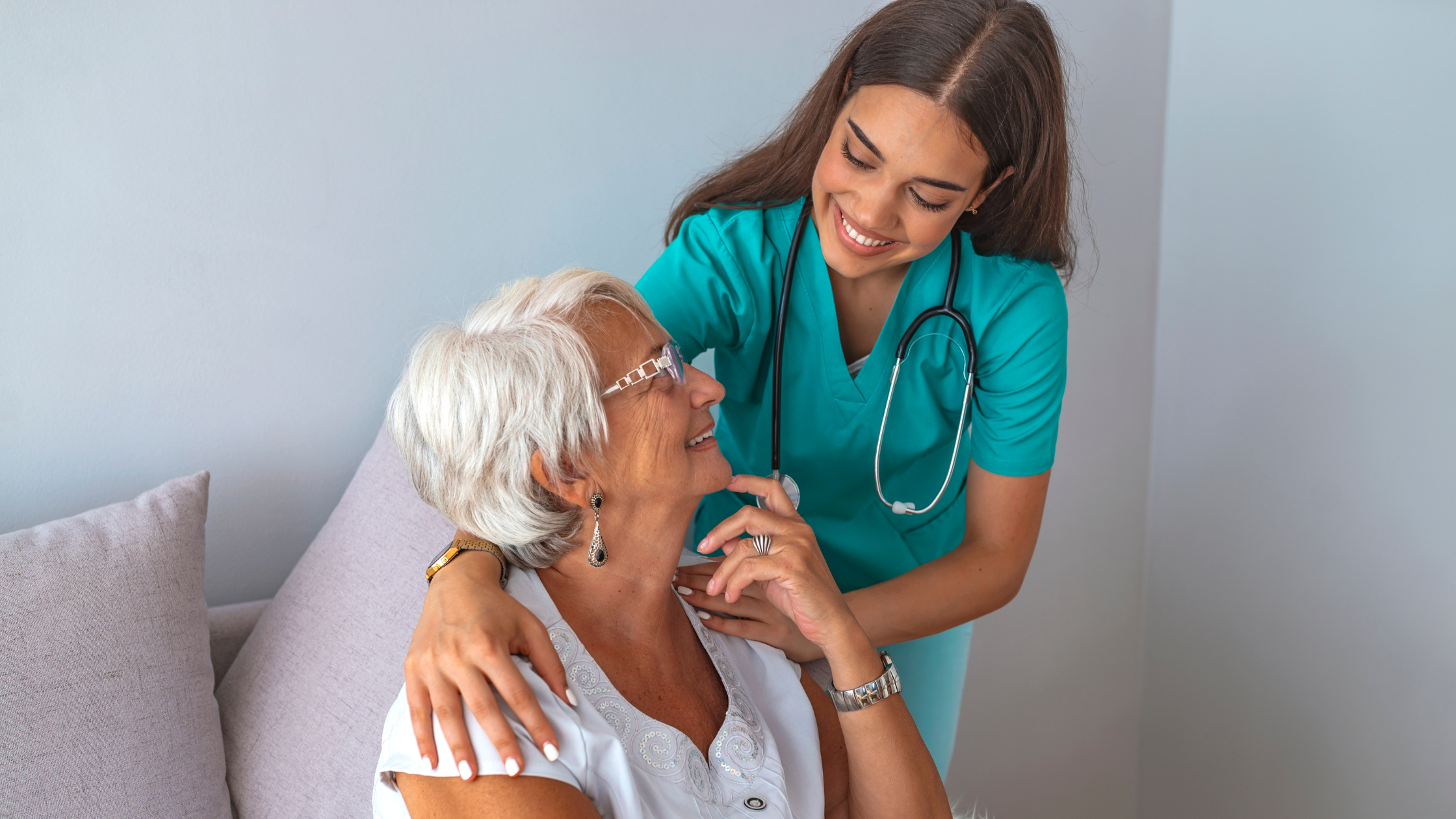 nurse with a stethoscope with their hands on a senior's shoulders