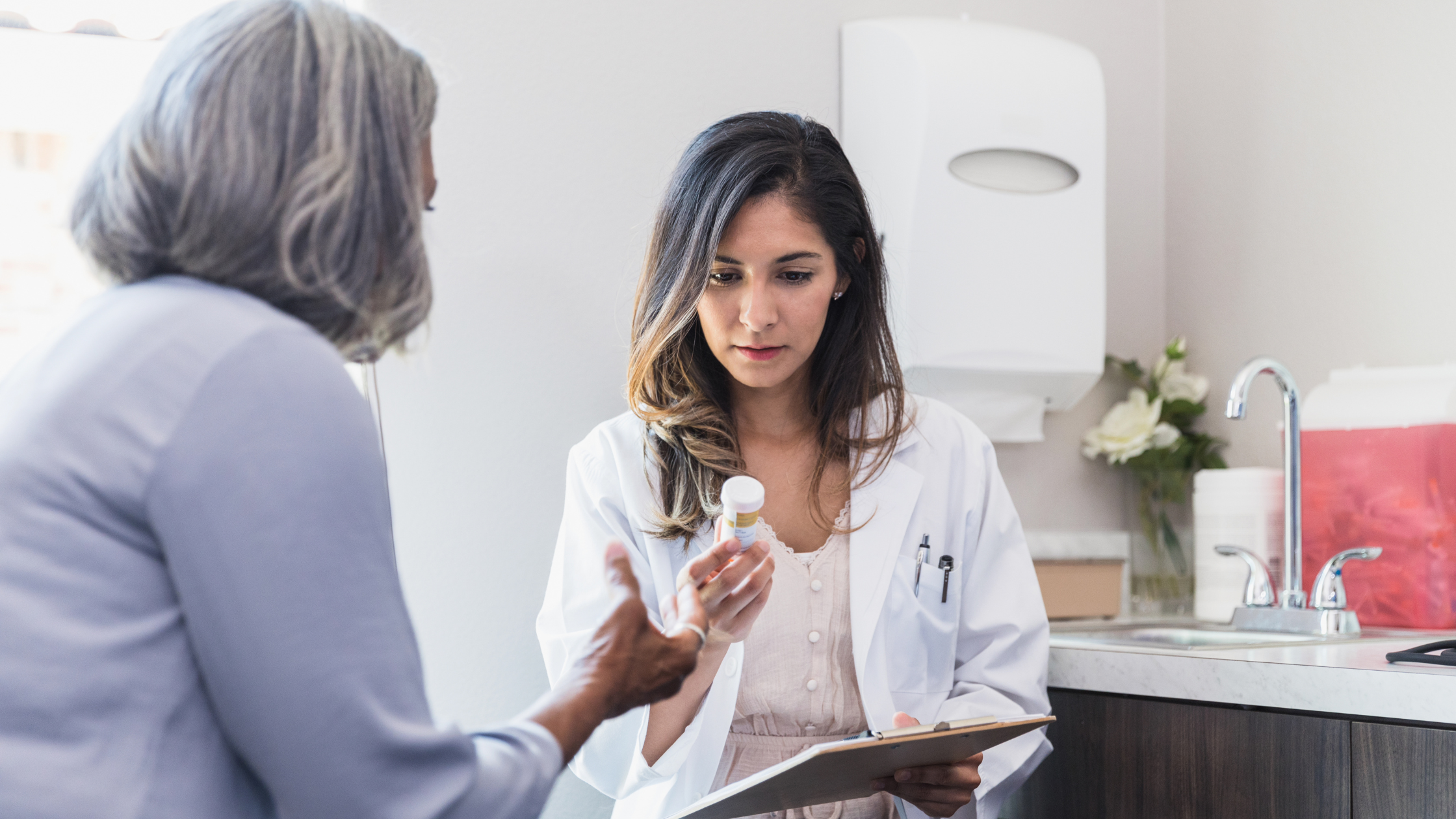 doctor holding a pill bottle out to a senior woman