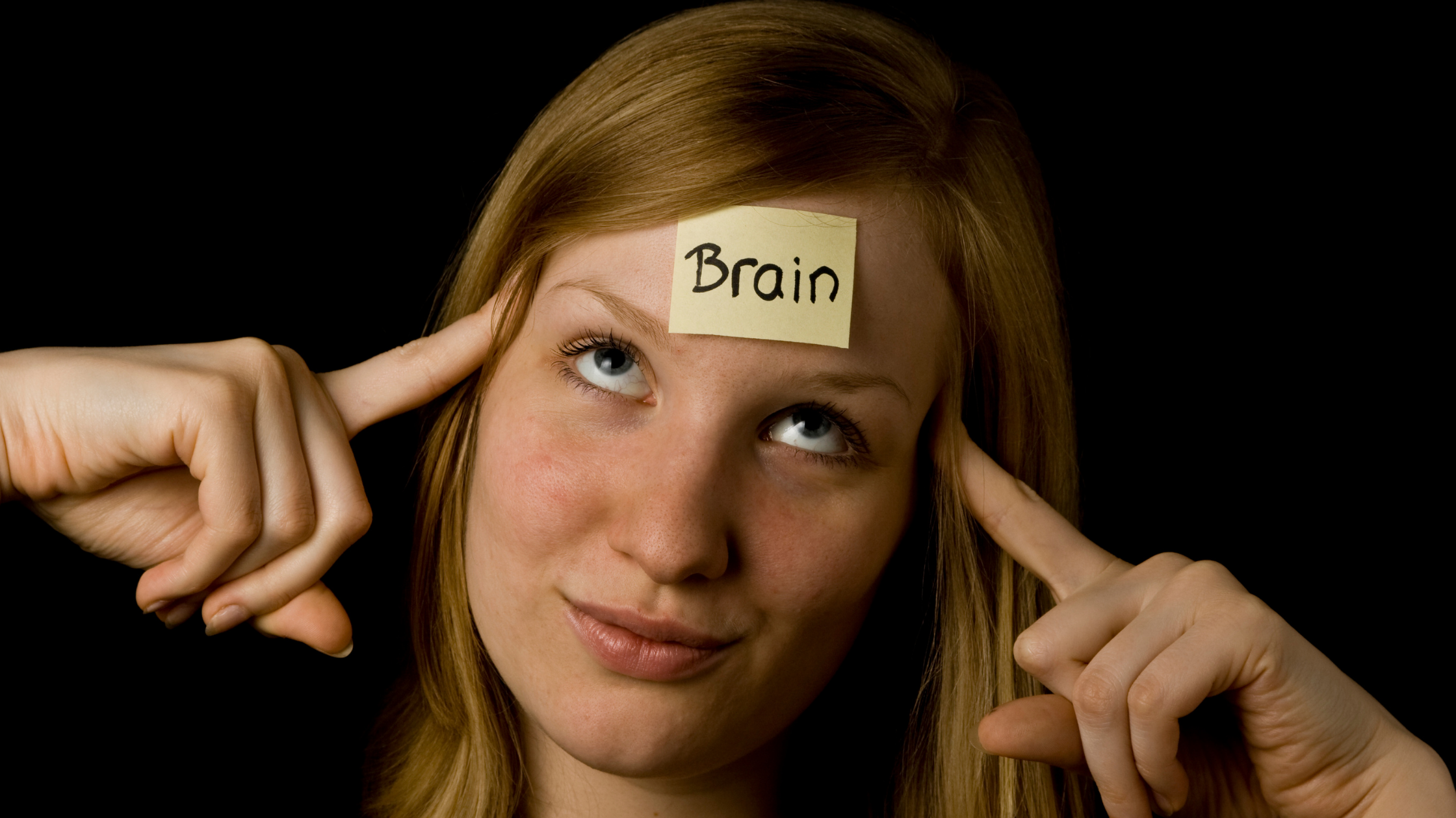 Woman with sticky note on her forehead that reads, "Brain", points at her head