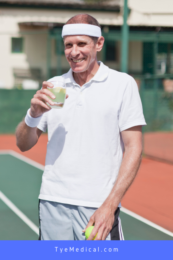 Smiling man takes a break from tennis to enjoy a fruit drink