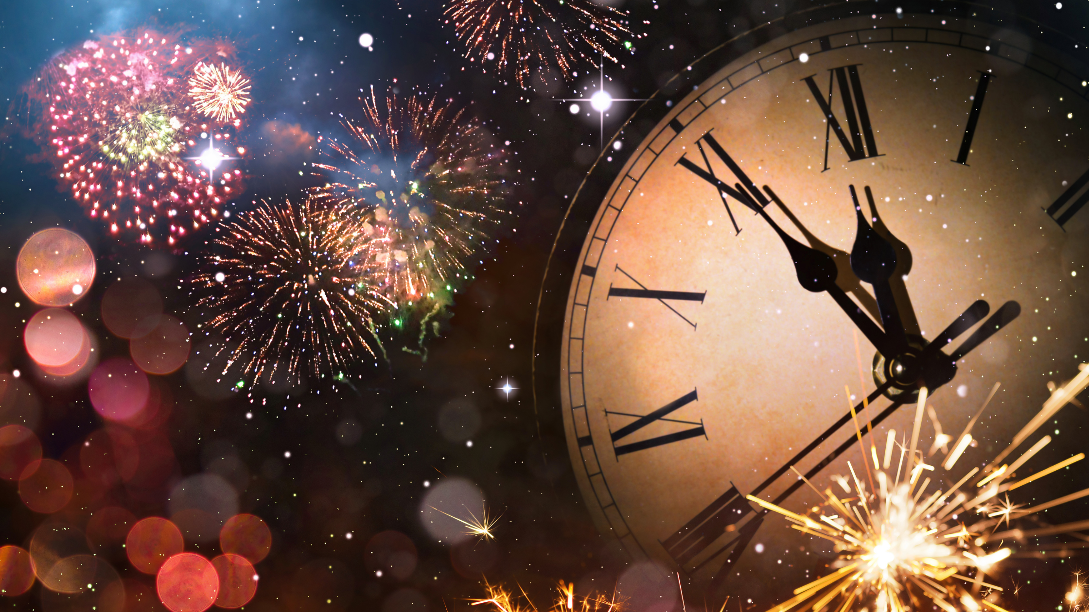 large analog clockfront surrounded by exploding fireworks