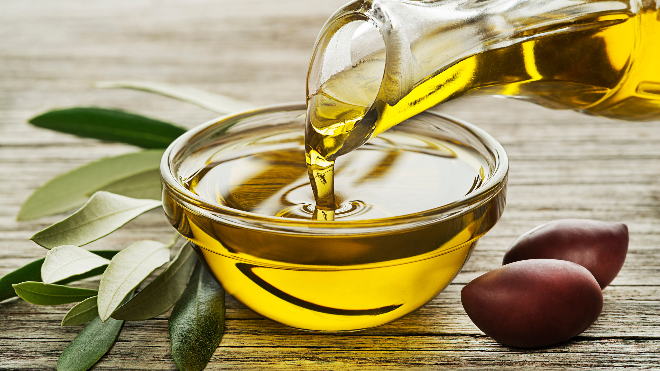 olive oil poring into a clear glass bowl