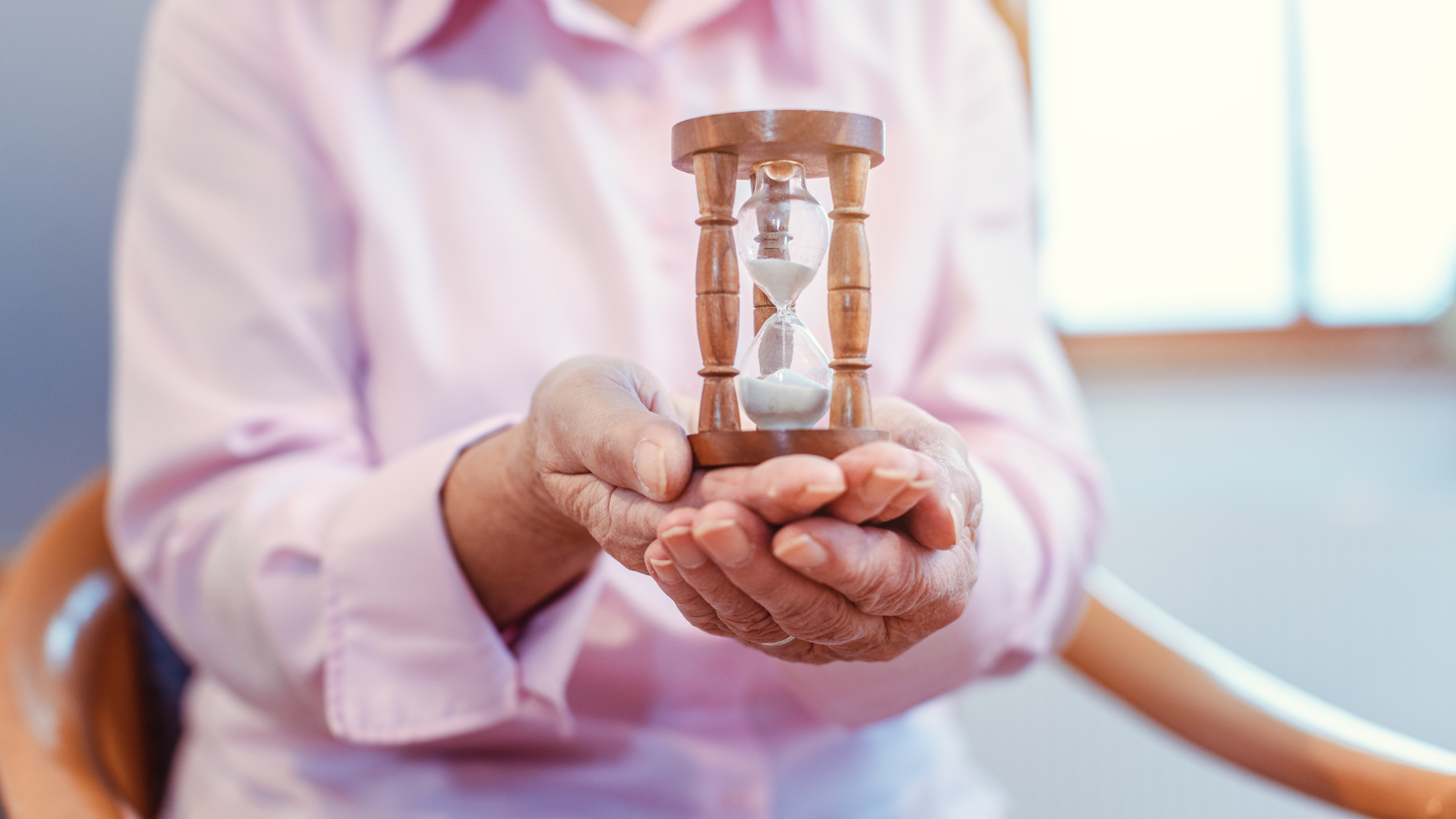 senior holds ornate hourglass in two hands