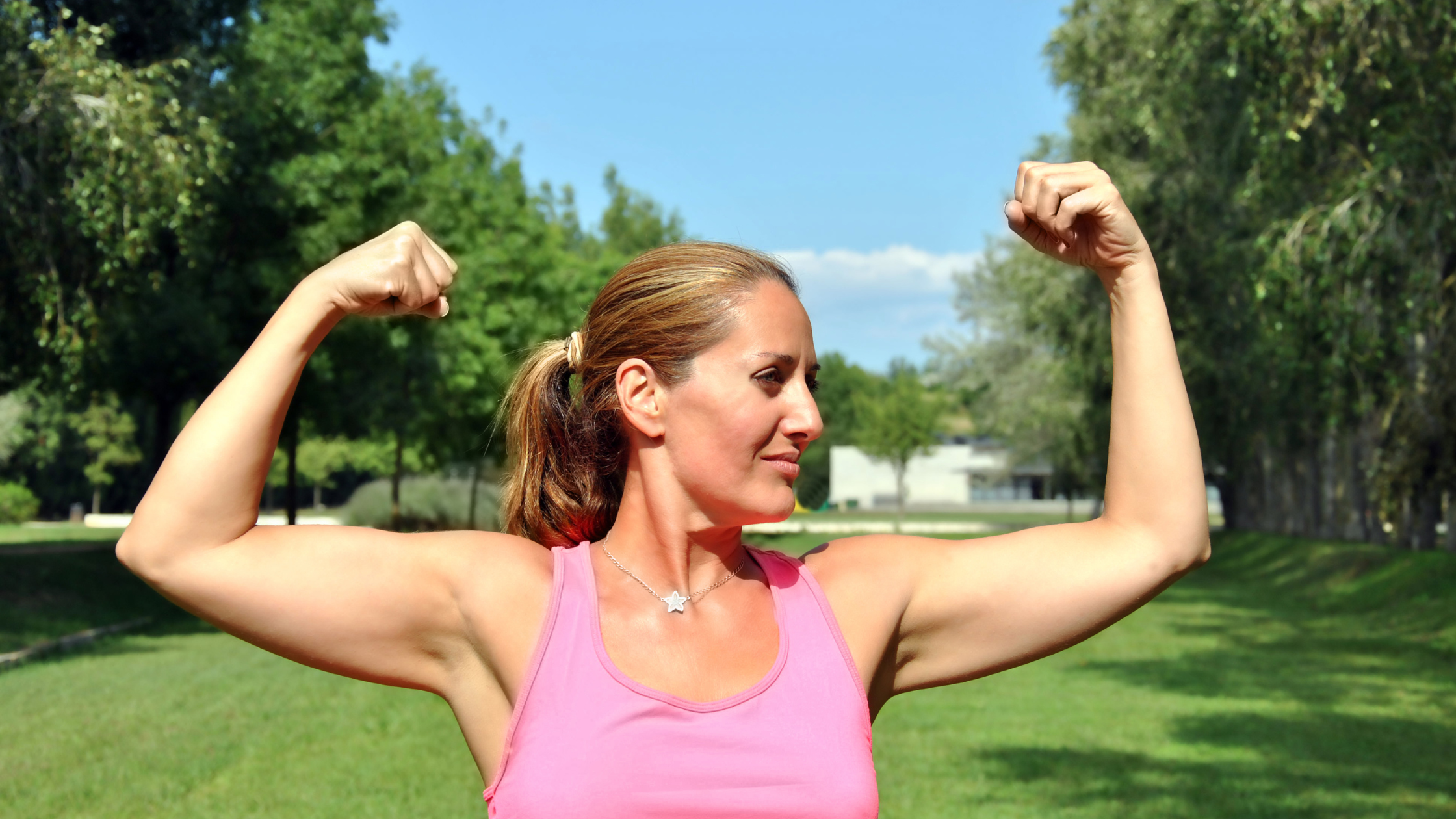 adult woman flexes her arm muscles while smiling