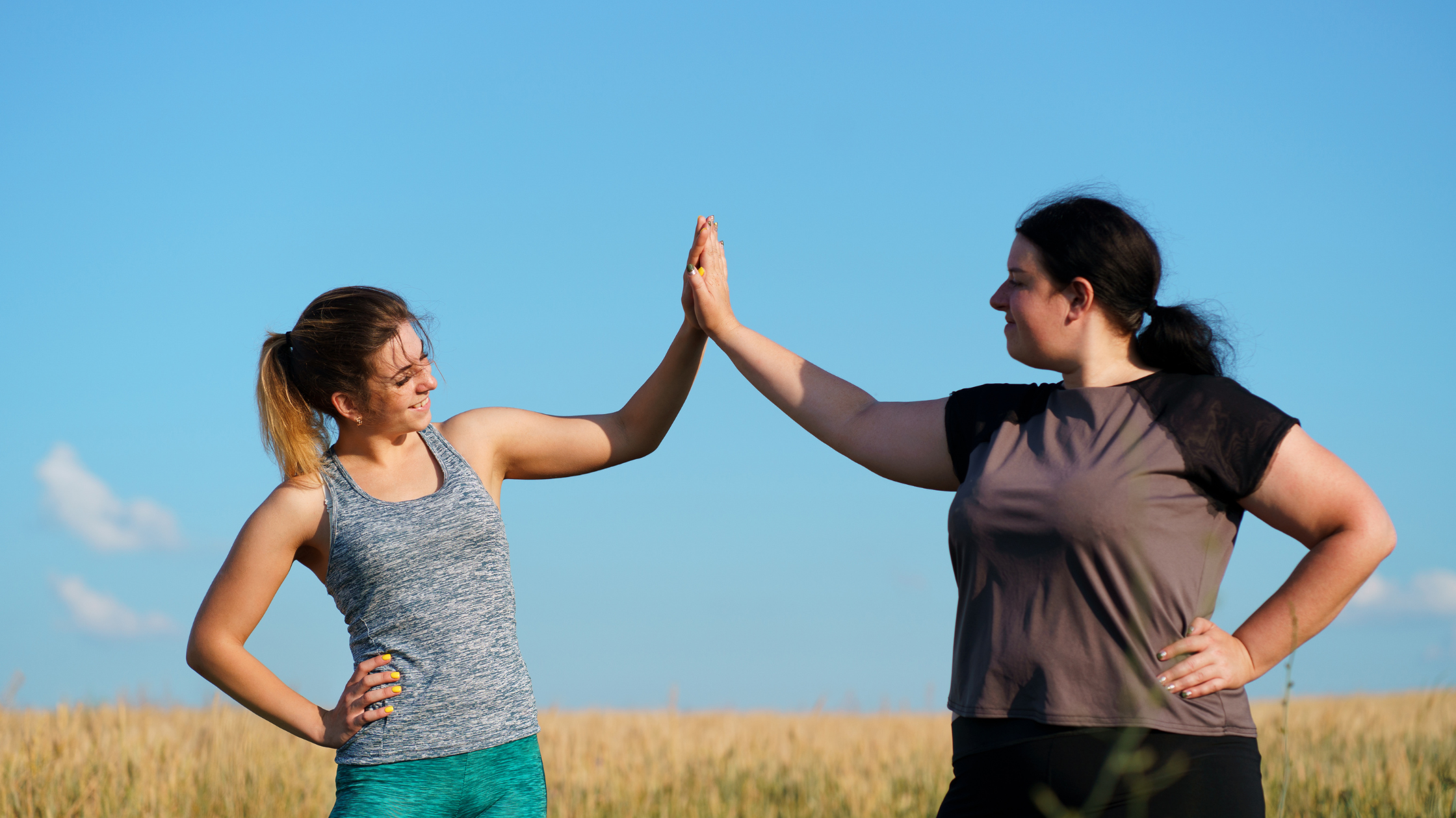 two women in workout gear high-five each other