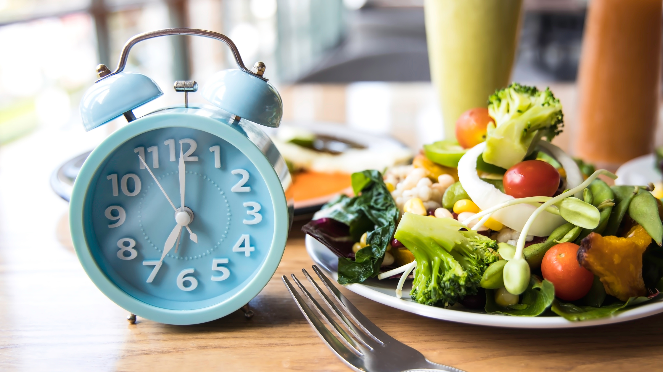 old-fashioned alarm clock sits beside a plate full of food