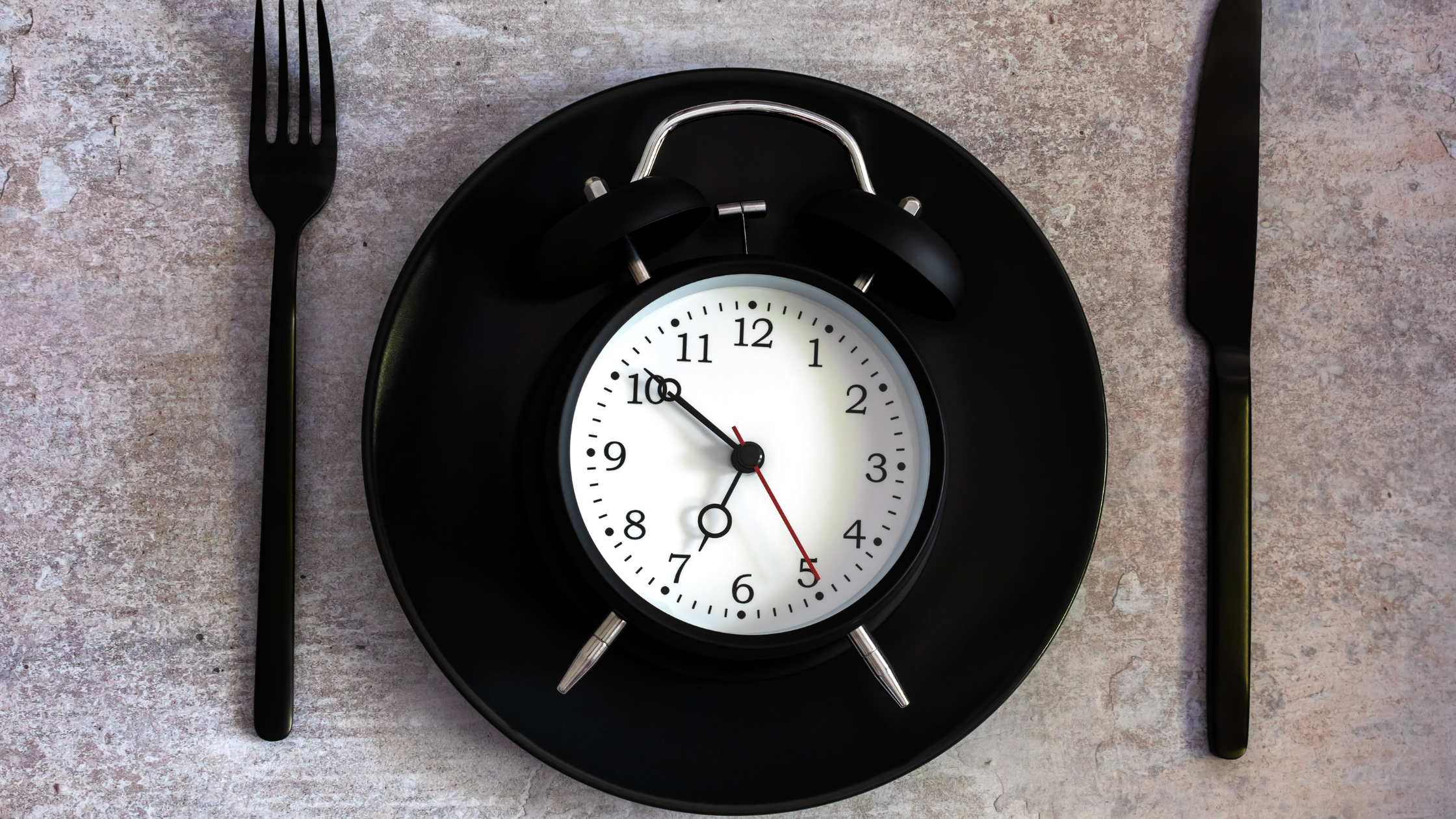 place setting with an analog alarm clock on the plate