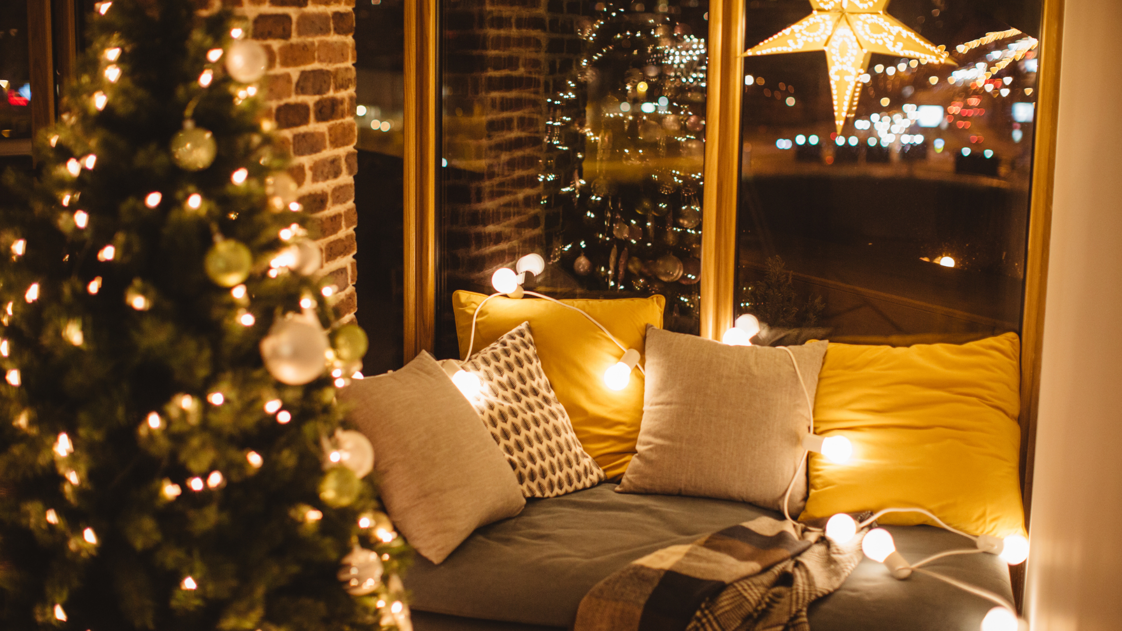 cozy setup with pillows, blankets, and lights in front of a Christmas tree