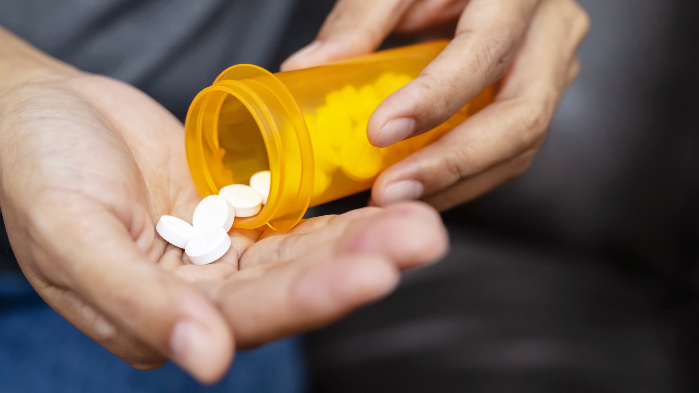 adult pours prescription pills onto their own hand