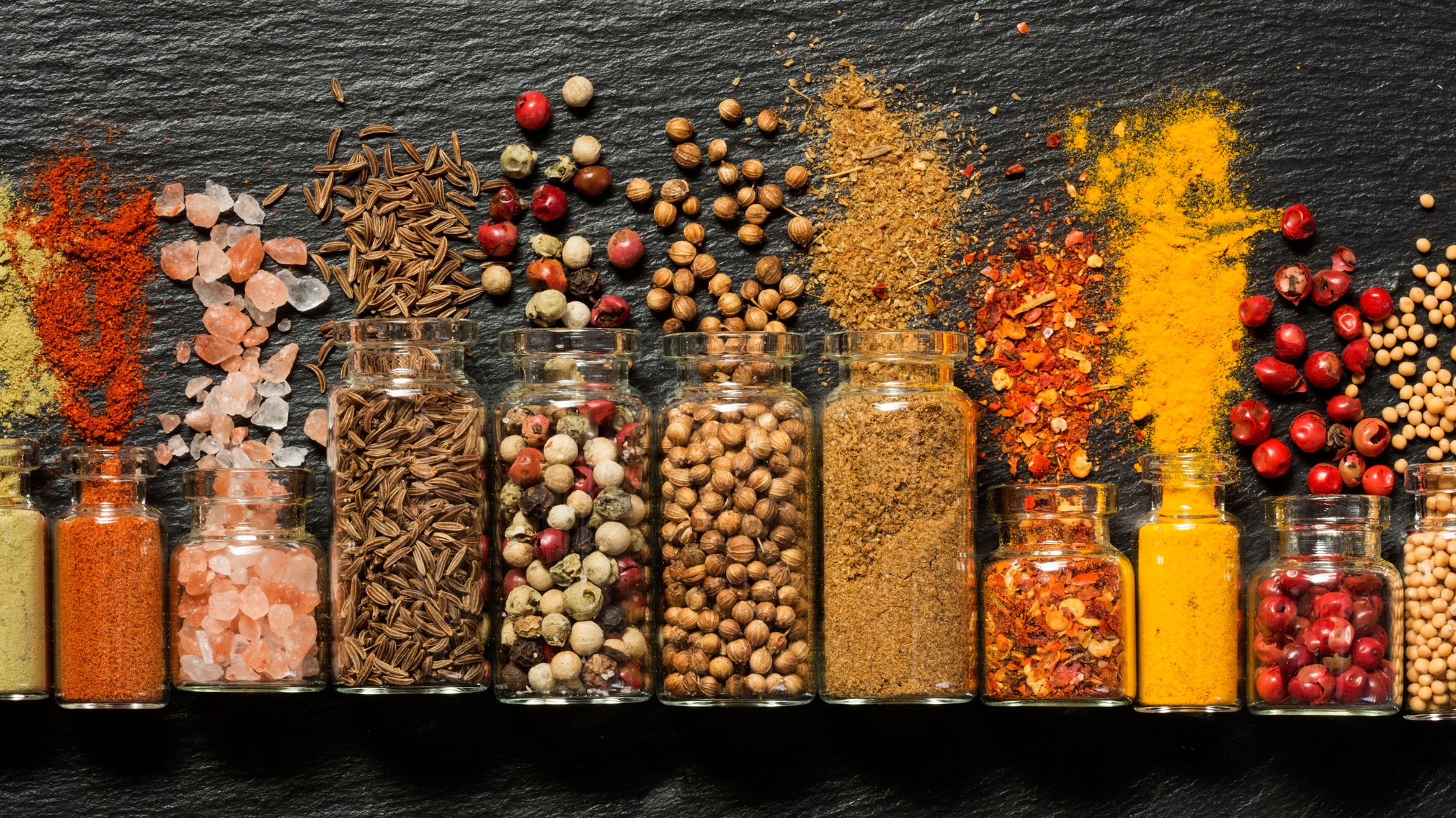 ten open jars on a table, various nuts and grains spilling out of them