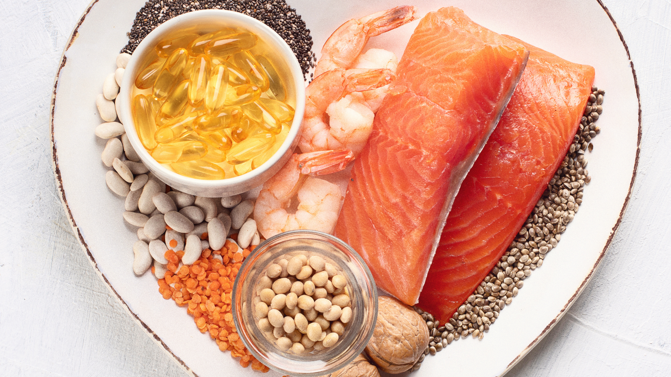 salmon, shrimp, uncooked grains, and pills on a plate