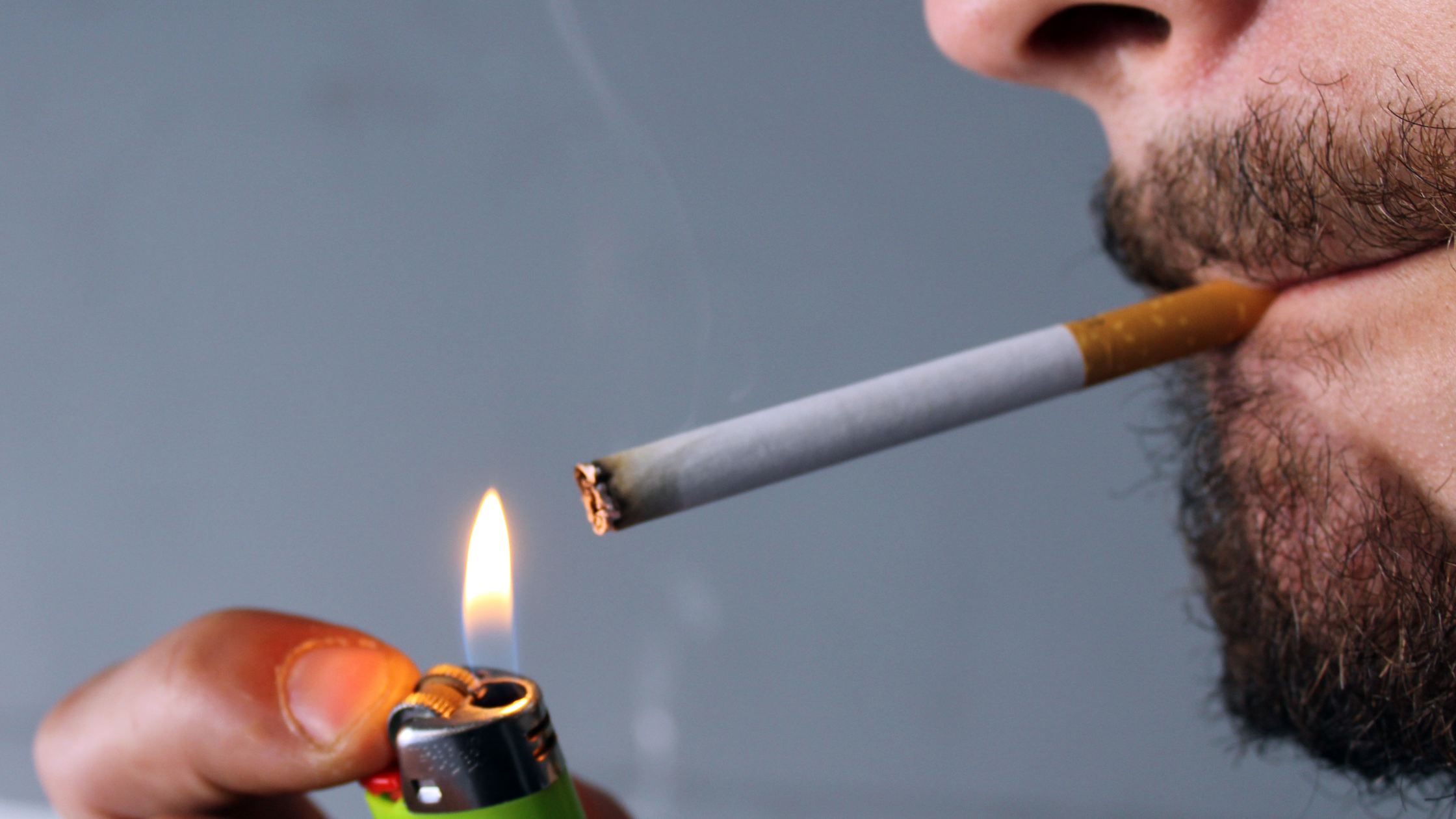 close up of a man lighting the cigarette in his mouth