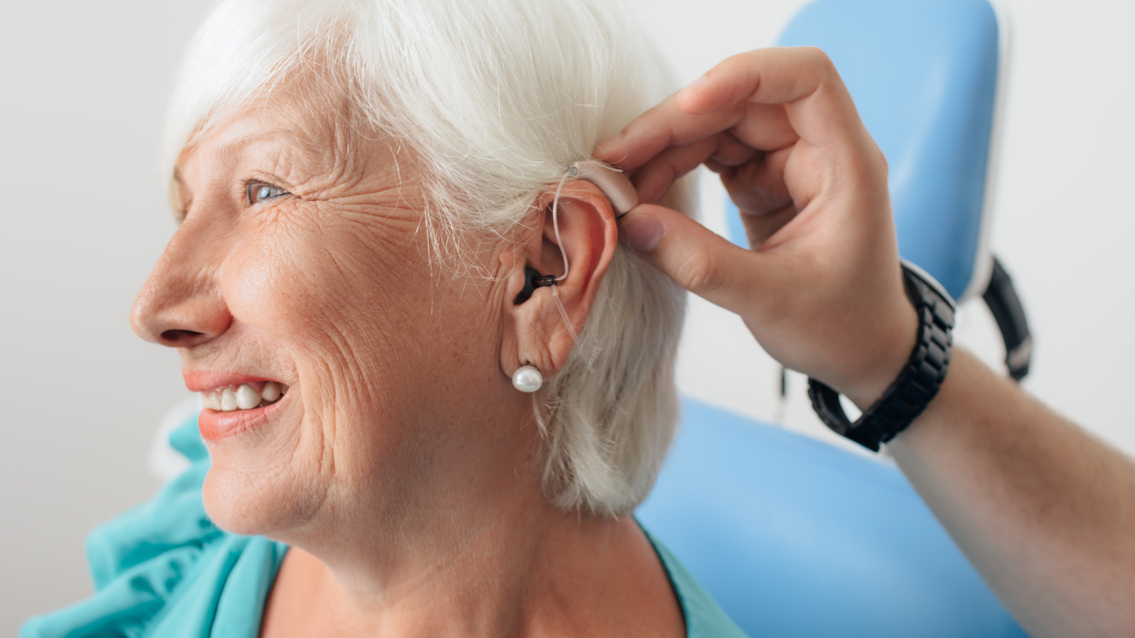 nurse fits a new hearing aide for a smiling senior woman