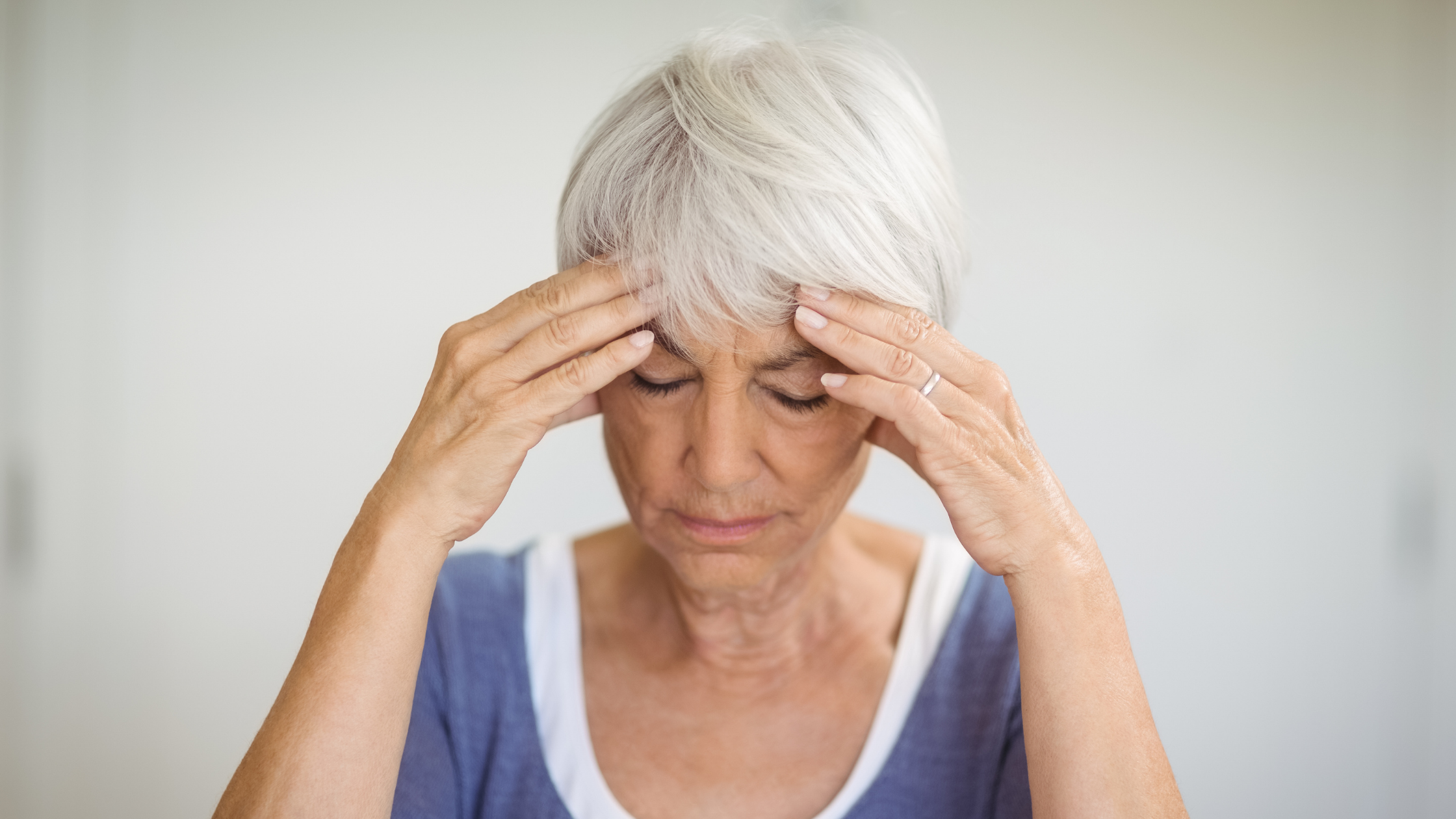 Senior woman with headache massaging her temples
