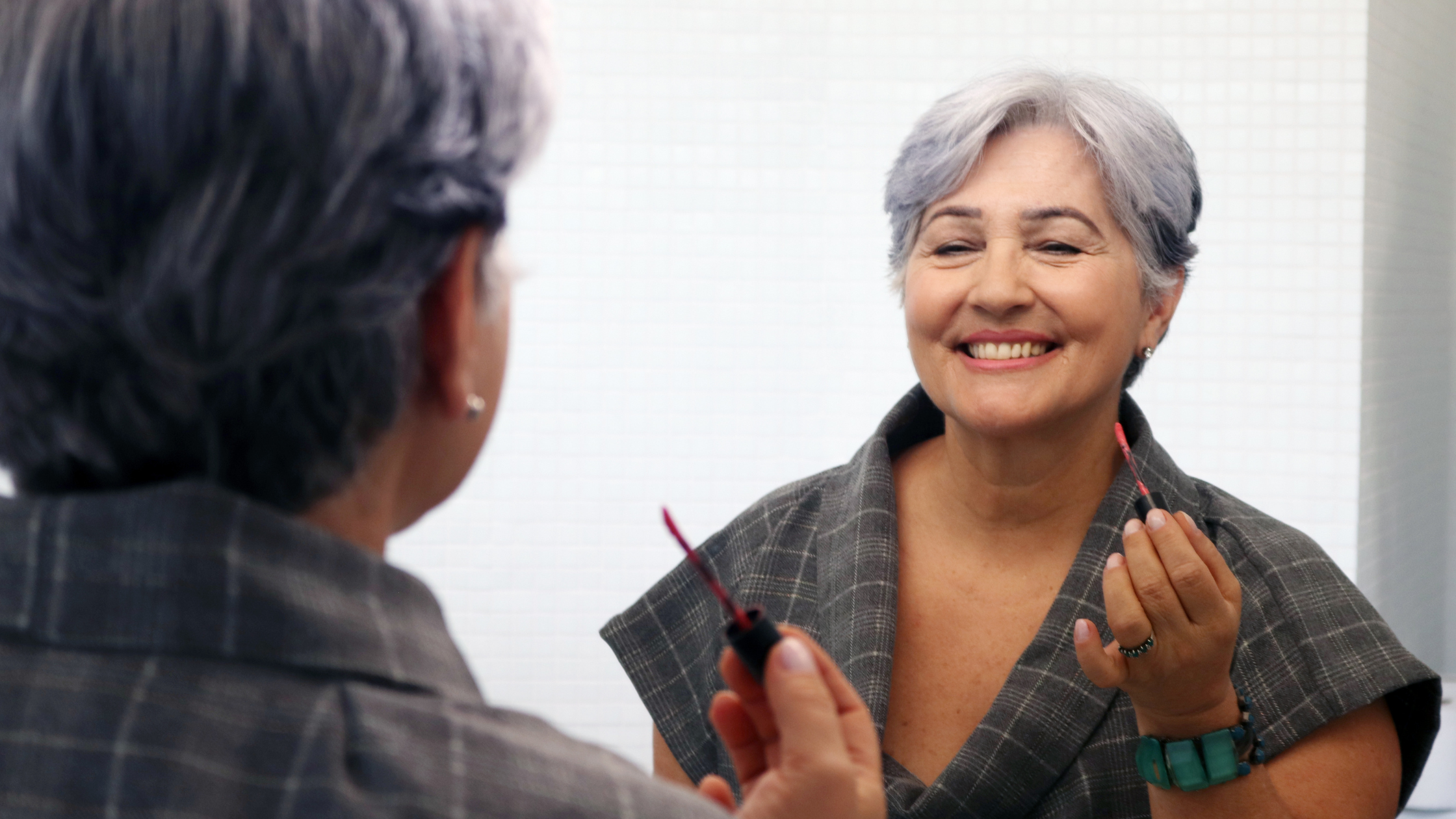 smiling senior woman applies lip gloss