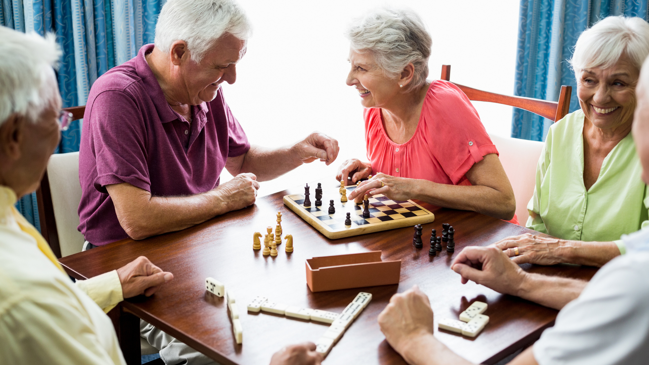 group of happy seniors playing tabletop games together