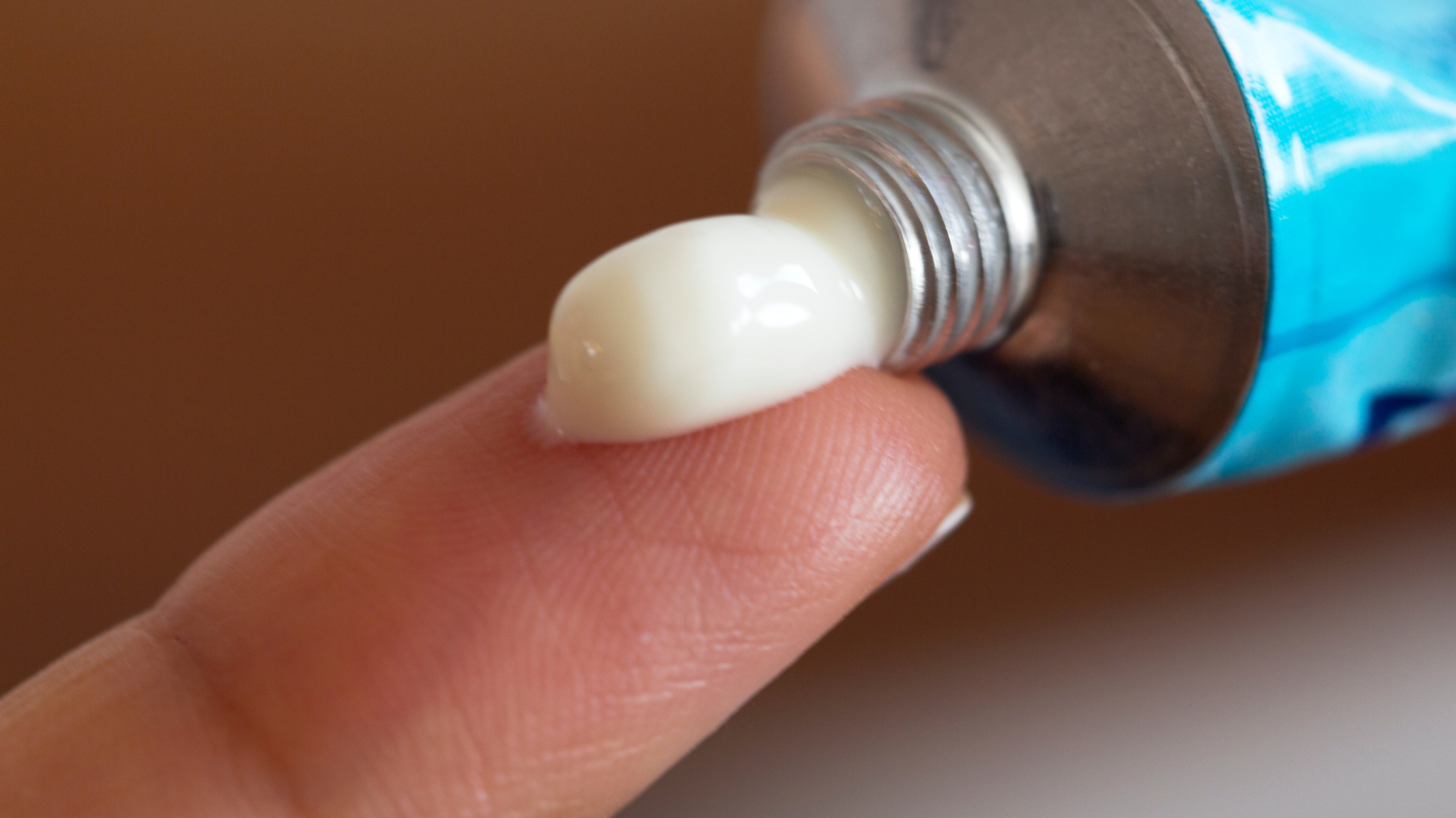 tube of cream being squeezed onto a finger